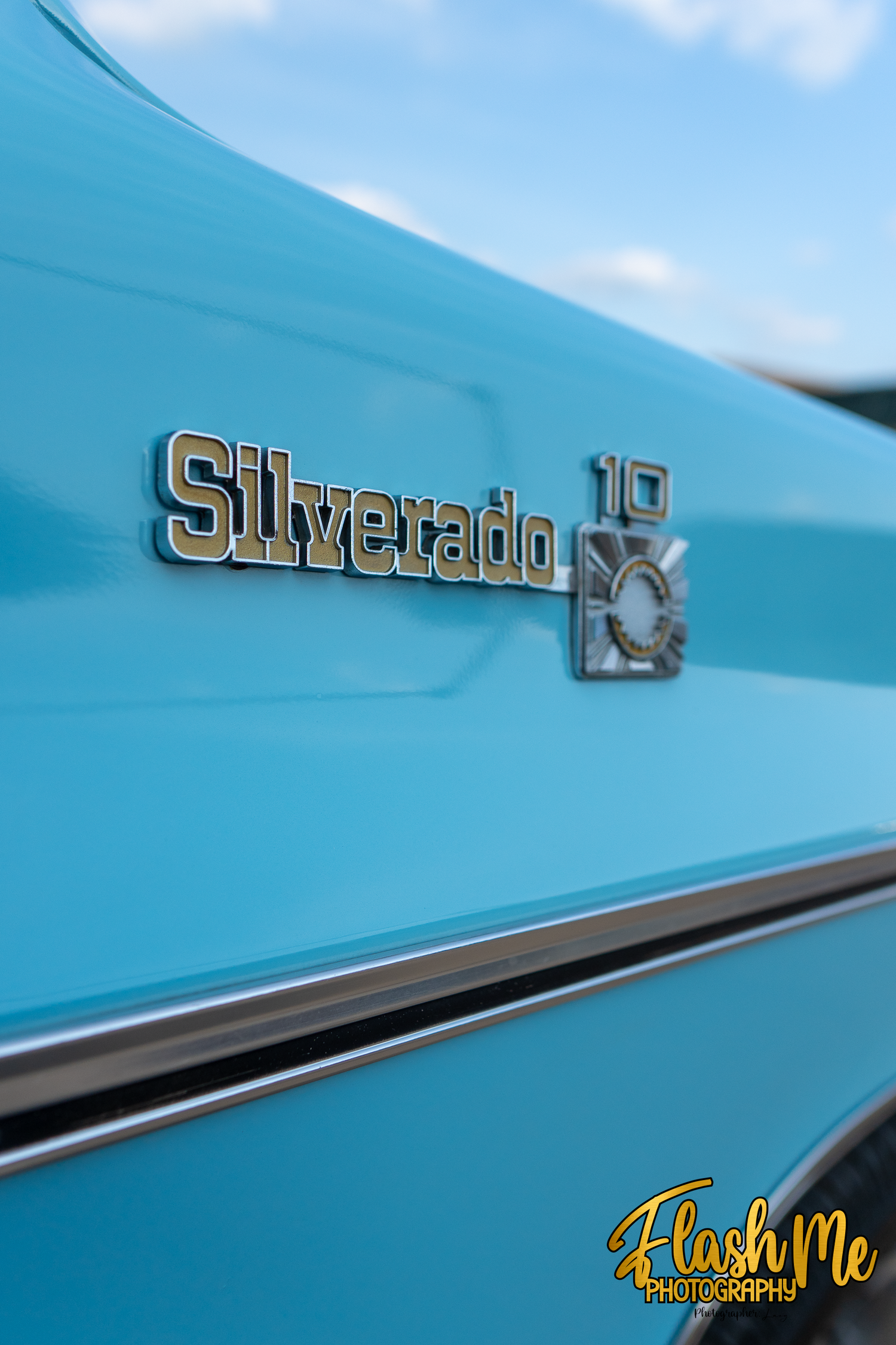 Close-up of a chrome Silverado 10 badge on a classic light blue Chevrolet truck body panel.