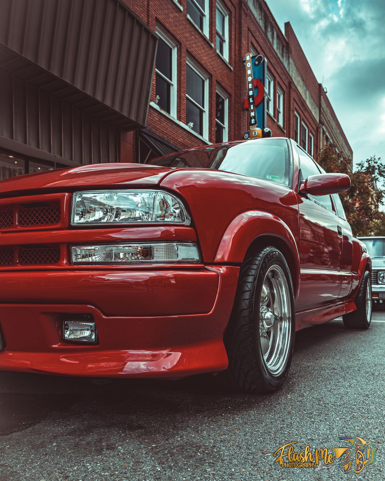 Red custom Chevrolet S10 pickup truck with body kit parked on a city street.