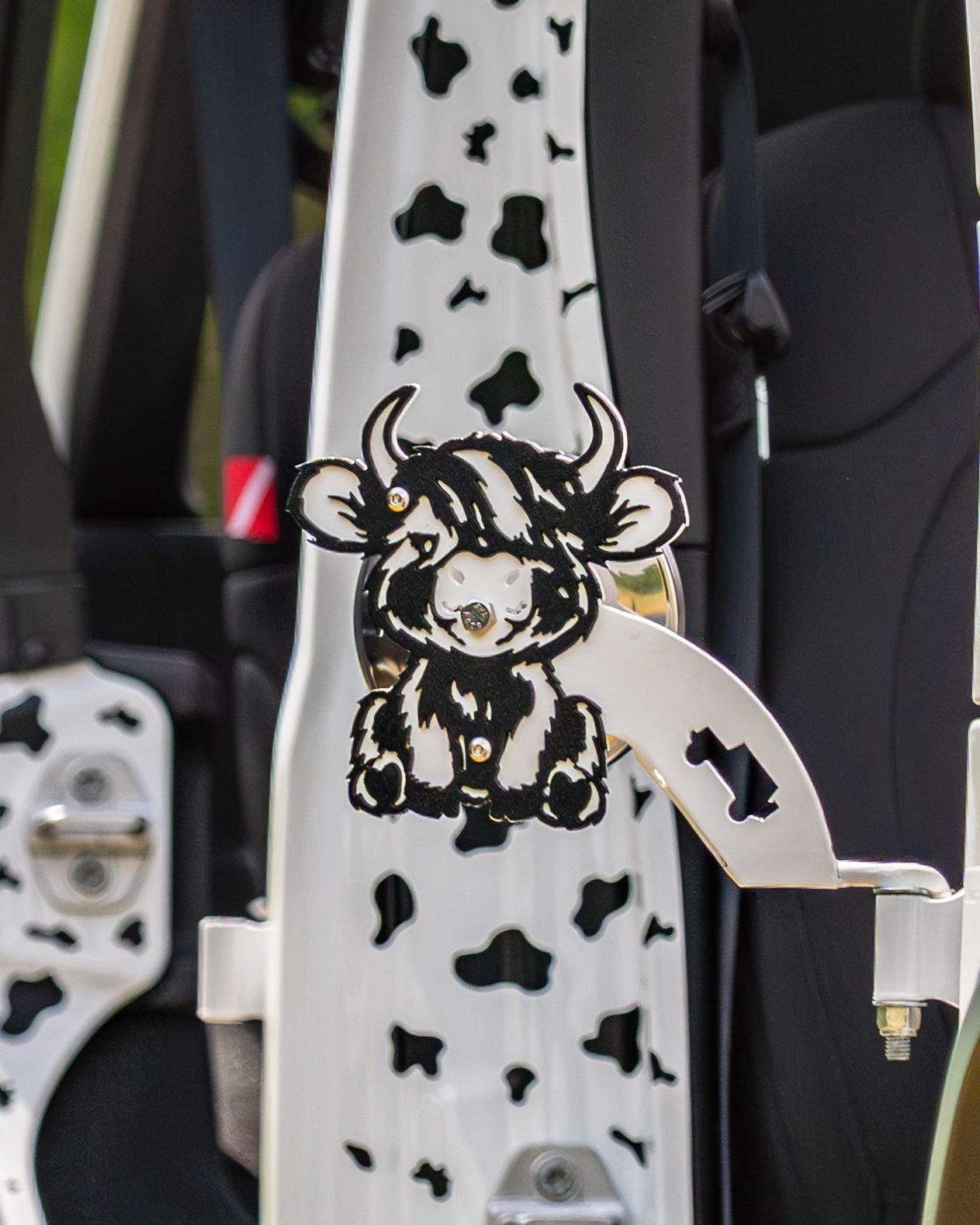 Custom cow print vehicle interior with a decorative Highland cow metal art ornament.