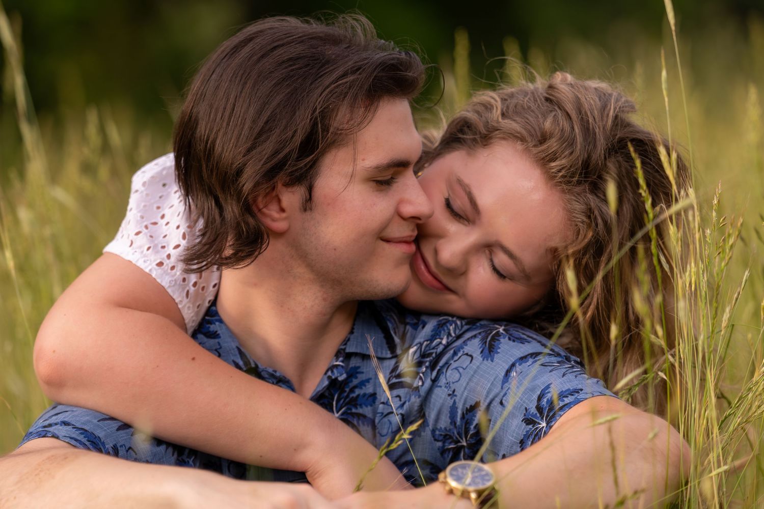 Romantic young couple sharing a close intimate moment together in a lush green field.