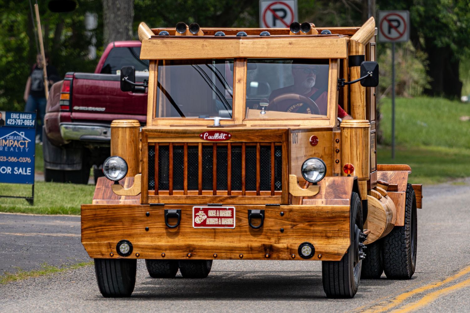 Unique handcrafted wooden truck driving down a road at a parade or show.