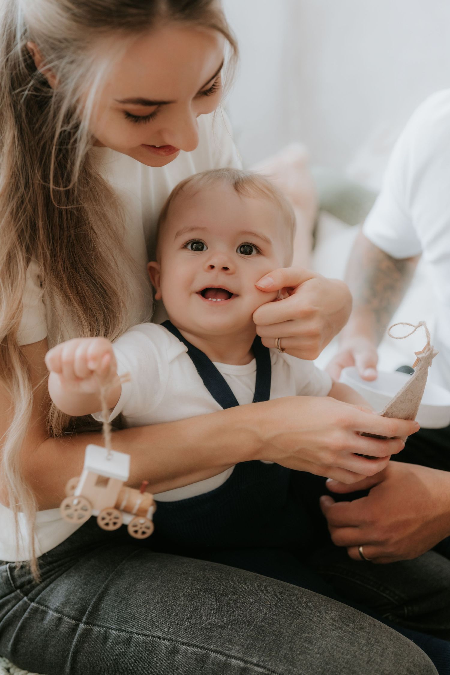 A young mother holds a happy smiling baby playing with wooden toys, sharing a joyful family moment together.