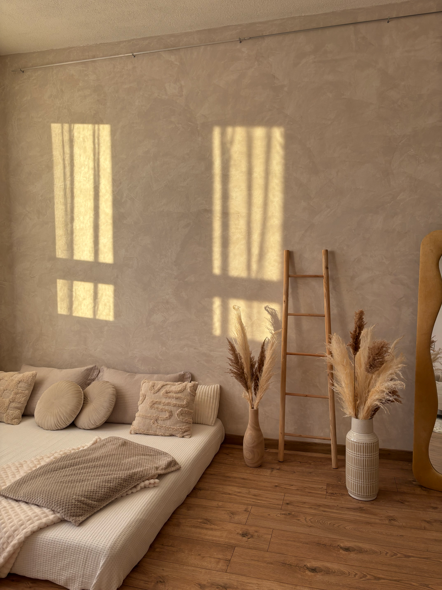 Warm sunlit boho bedroom with pampas grass, wooden ladder, and neutral beige tones.