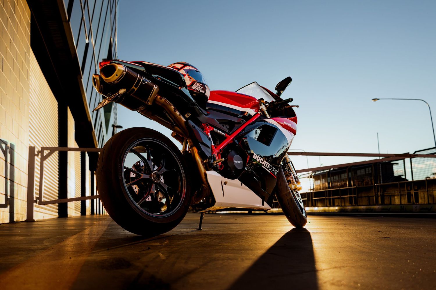 Red and white sportbike parked in golden hour light beneath a building