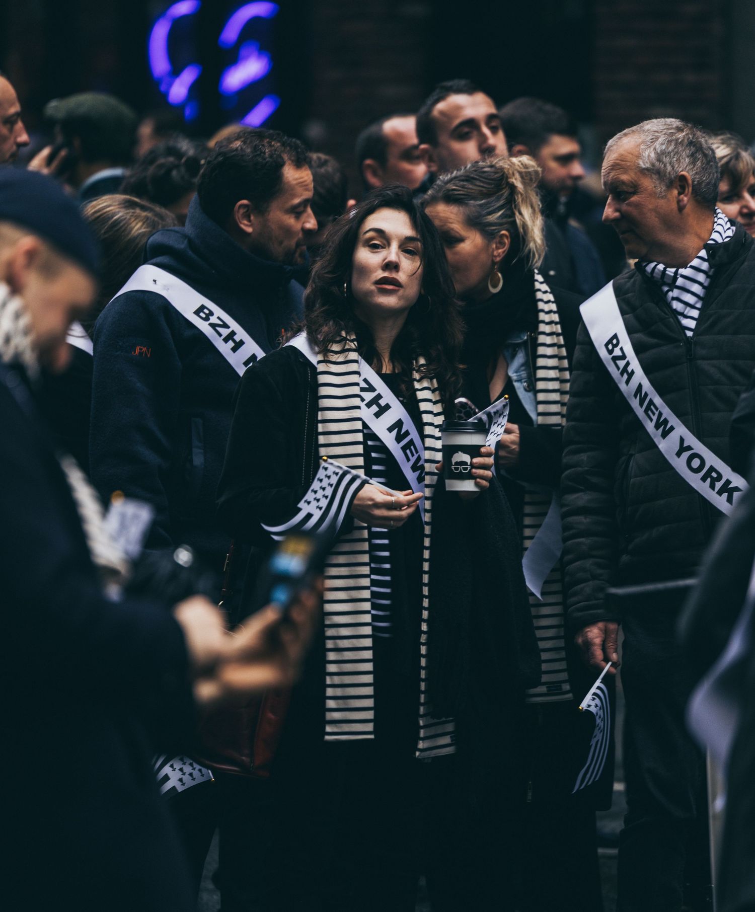 Group of people wearing BZH New York sashes gathered together at an outdoor parade event.