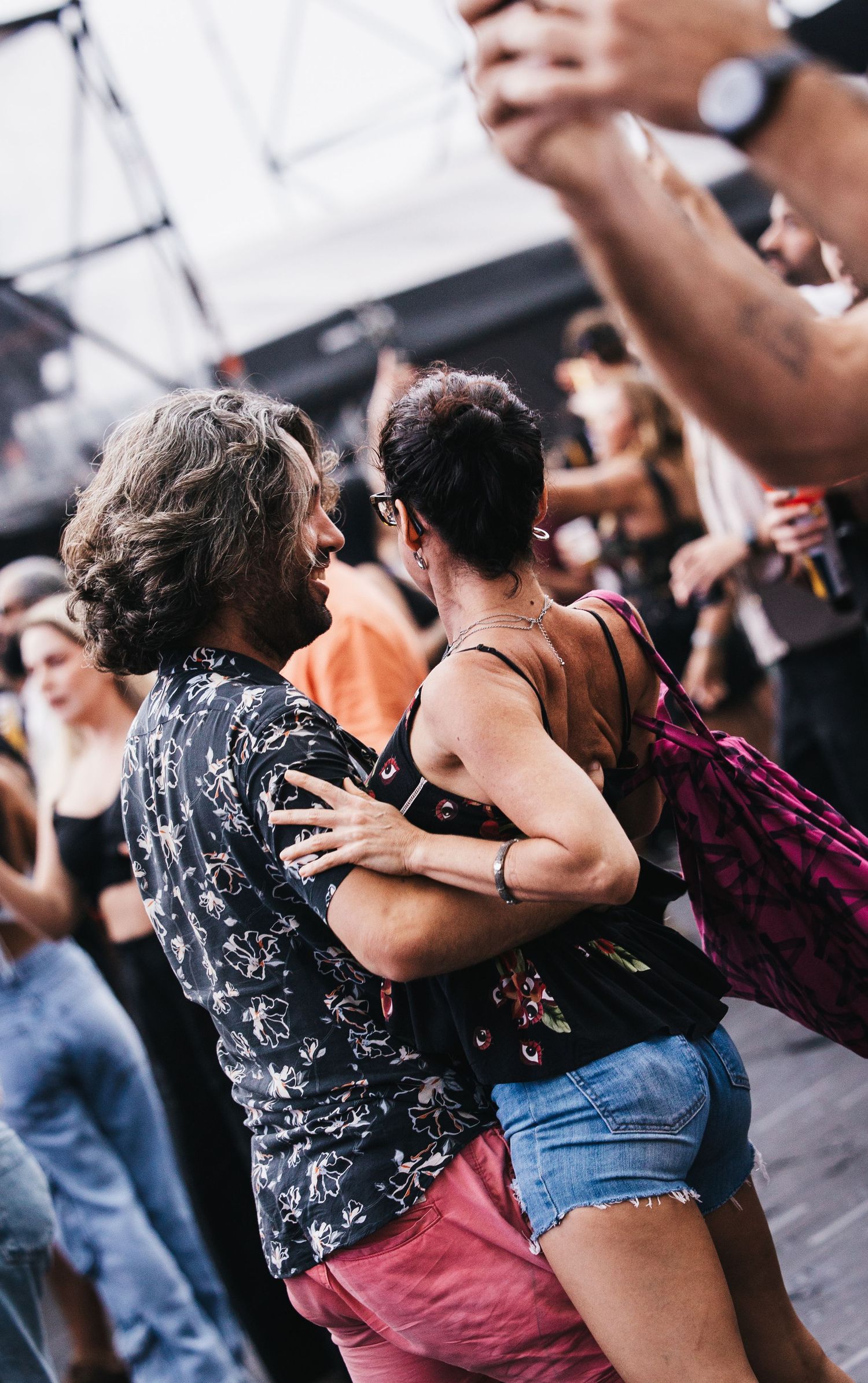Couple dancing closely together at a lively outdoor dance event surrounded by other dancers.