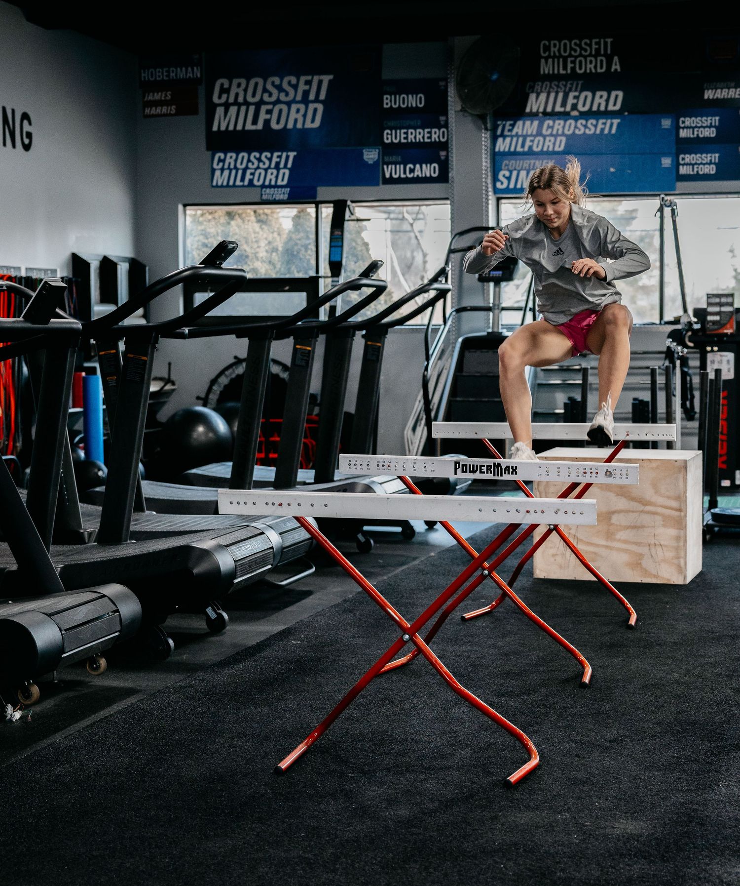 Athlete performing a box jump at CrossFit Milford gym, landing on a FoamBox plyo box surrounded by fitness equipment.
