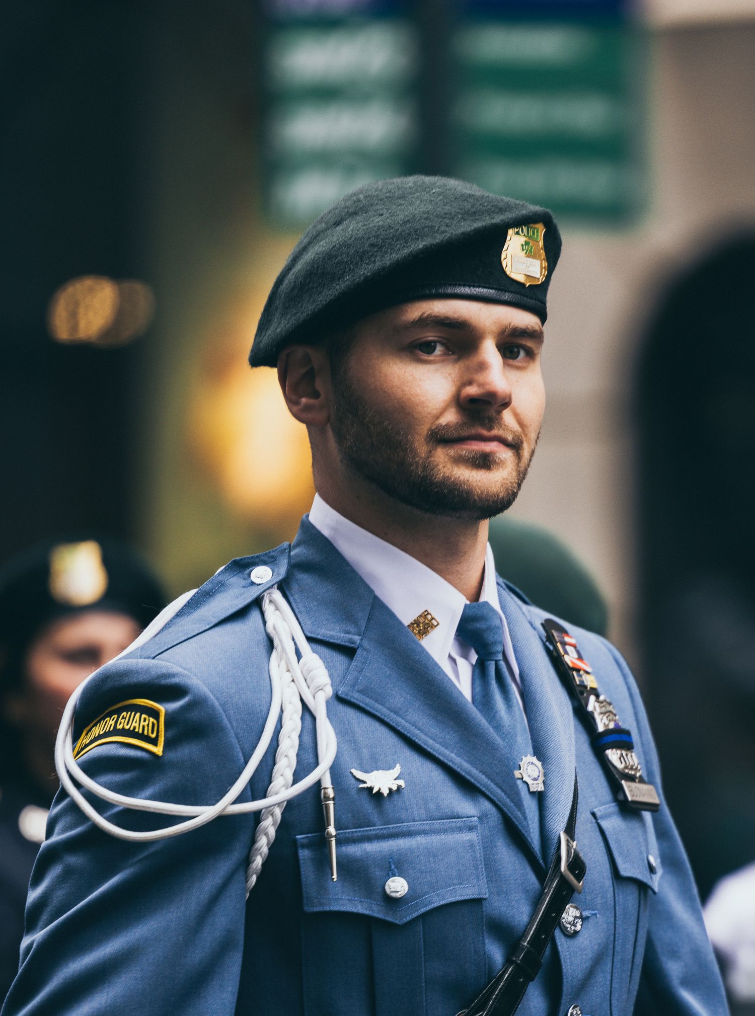 Young man in blue honor guard uniform and green beret at formal ceremony.