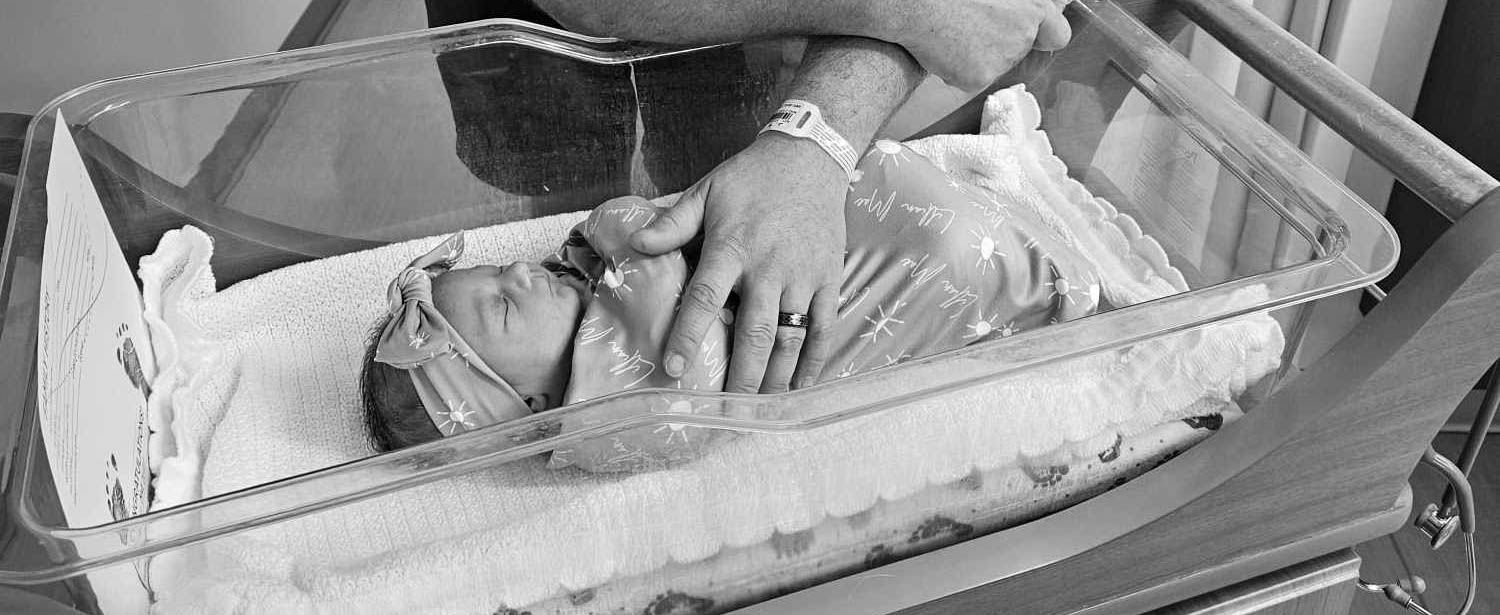 Black and white photo of a newborn baby resting in a hospital bassinet during the first 48 hours