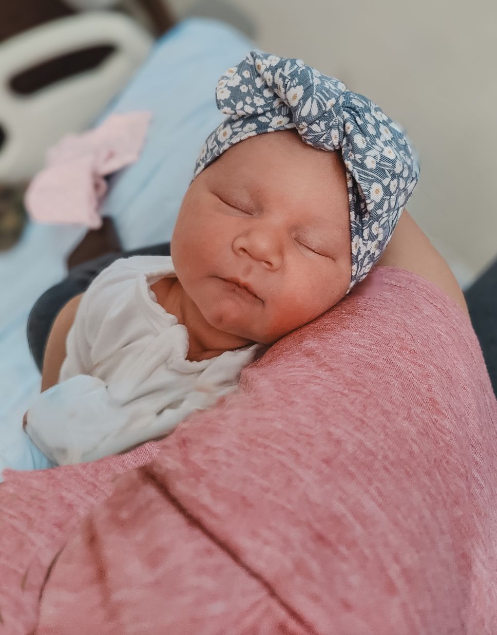 Sleeping newborn baby wearing a soft headband, photographed in natural window light during the first days after birth