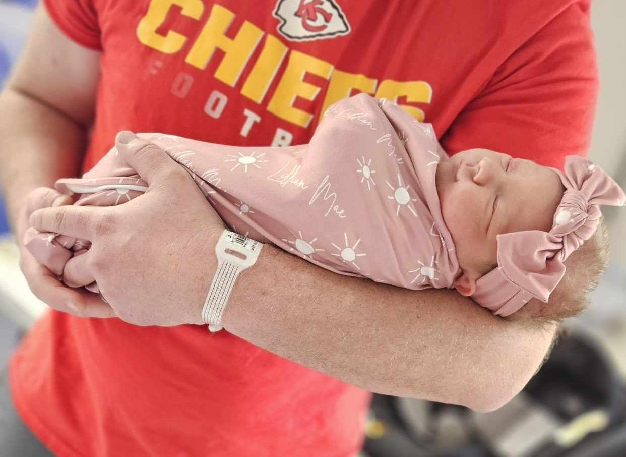 Parent holding a newborn baby close during a quiet lifestyle newborn moment at home