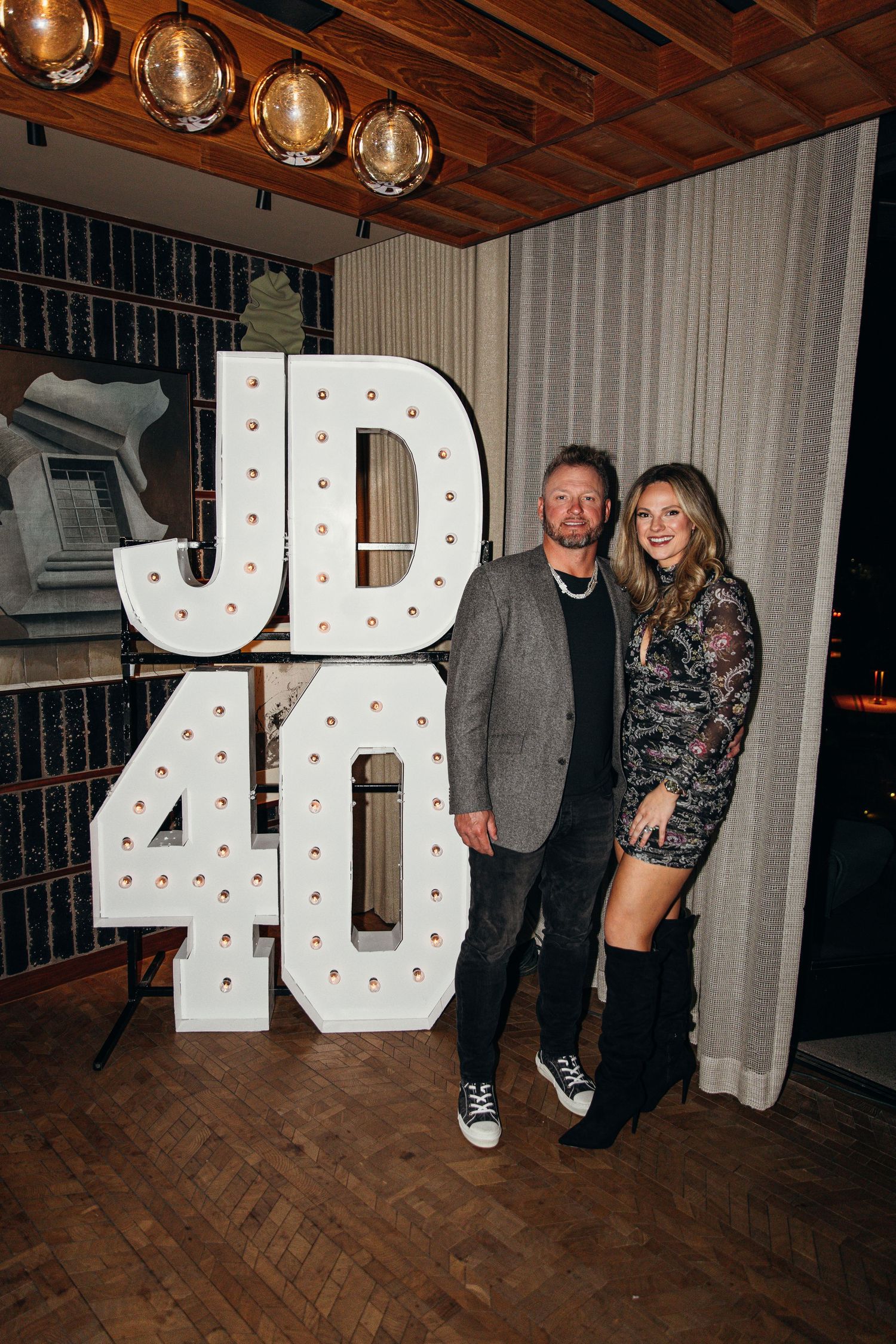 Couple posing in front of illuminated JD40 marquee letter signs at a 40th birthday celebration event.