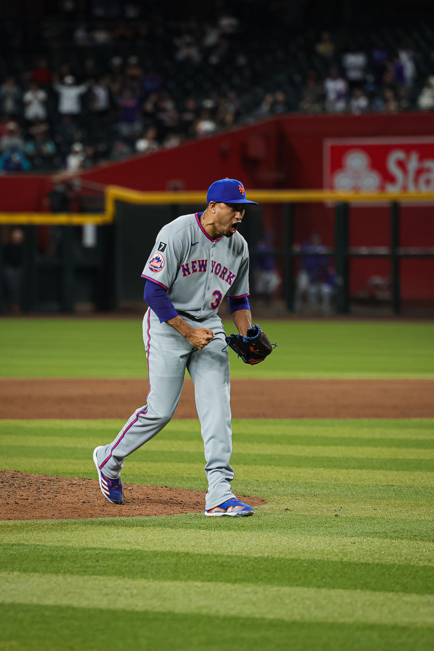 New York Mets pitcher celebrating on mound in gray away uniform during MLB game.