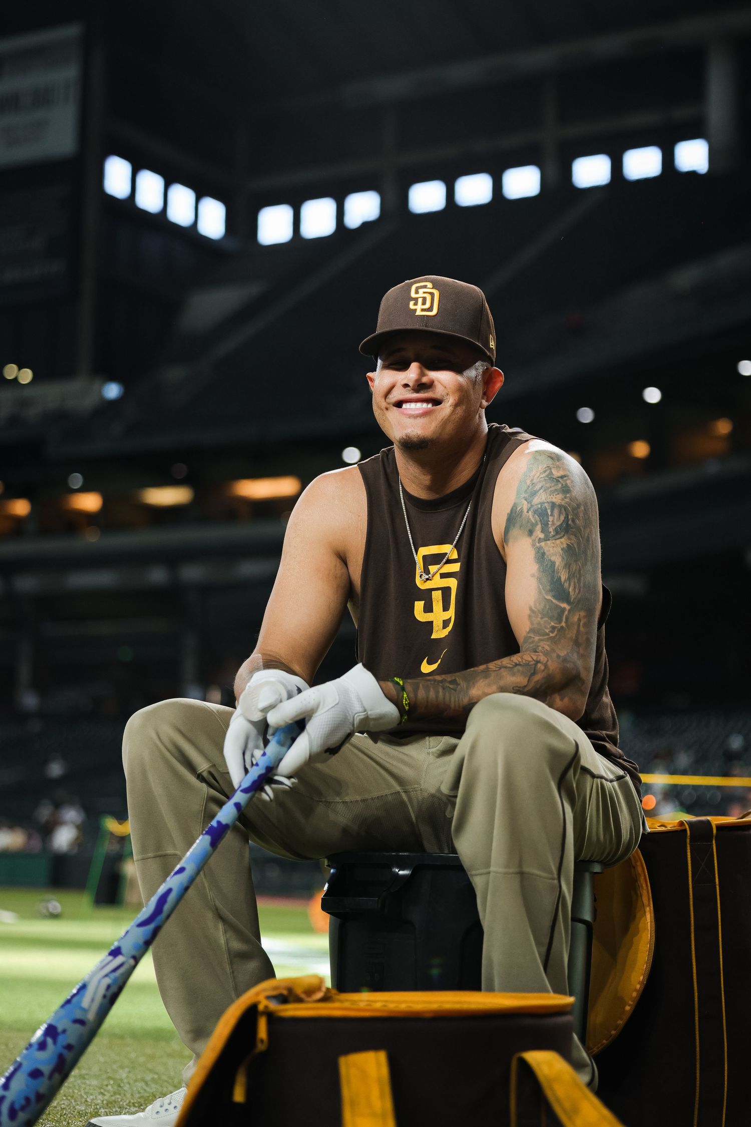 San Diego Padres player sits smiling with bat and batting gloves during pre-game.