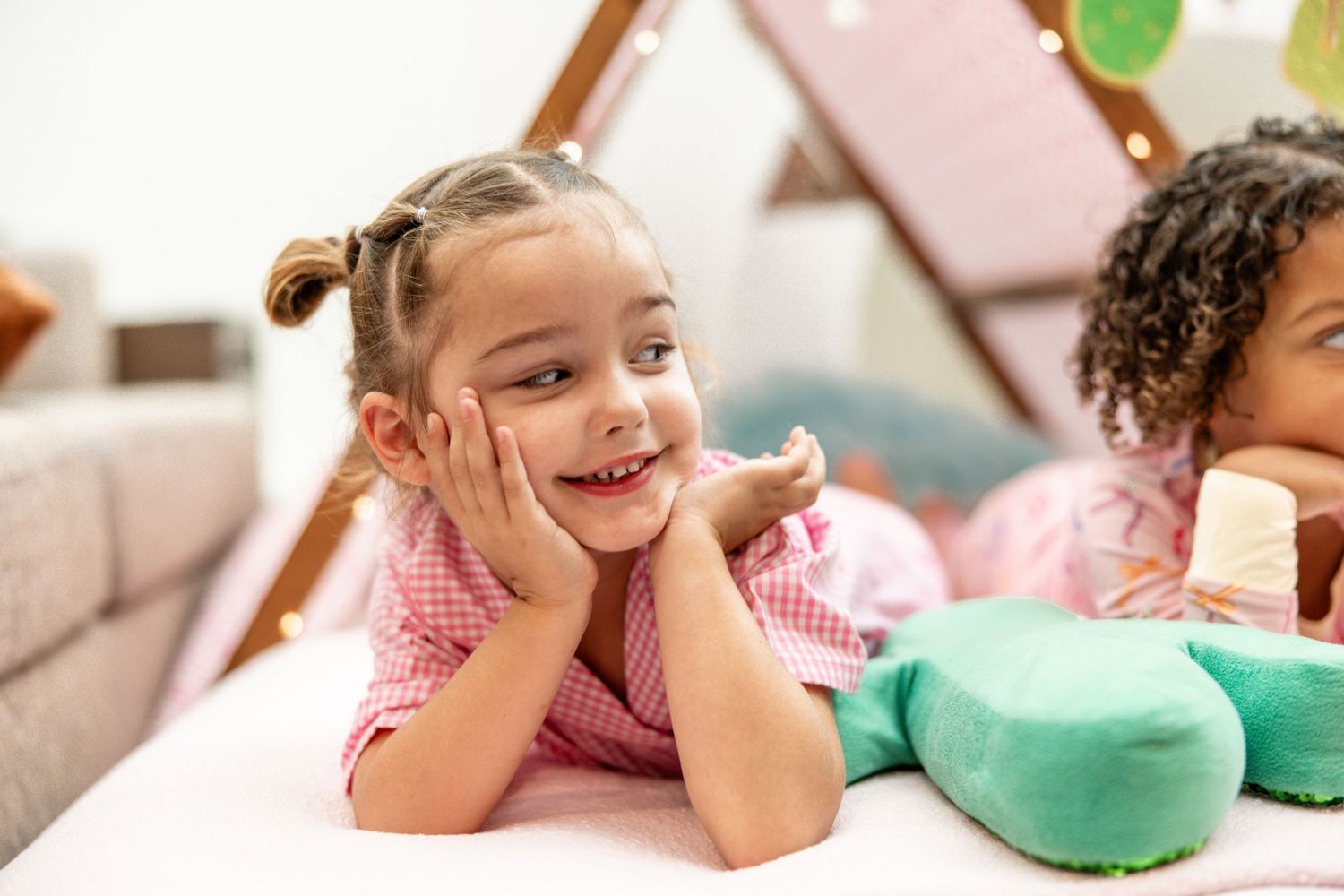 Adorable little girl smiling with hands on cheeks during a kids teepee sleepover party.