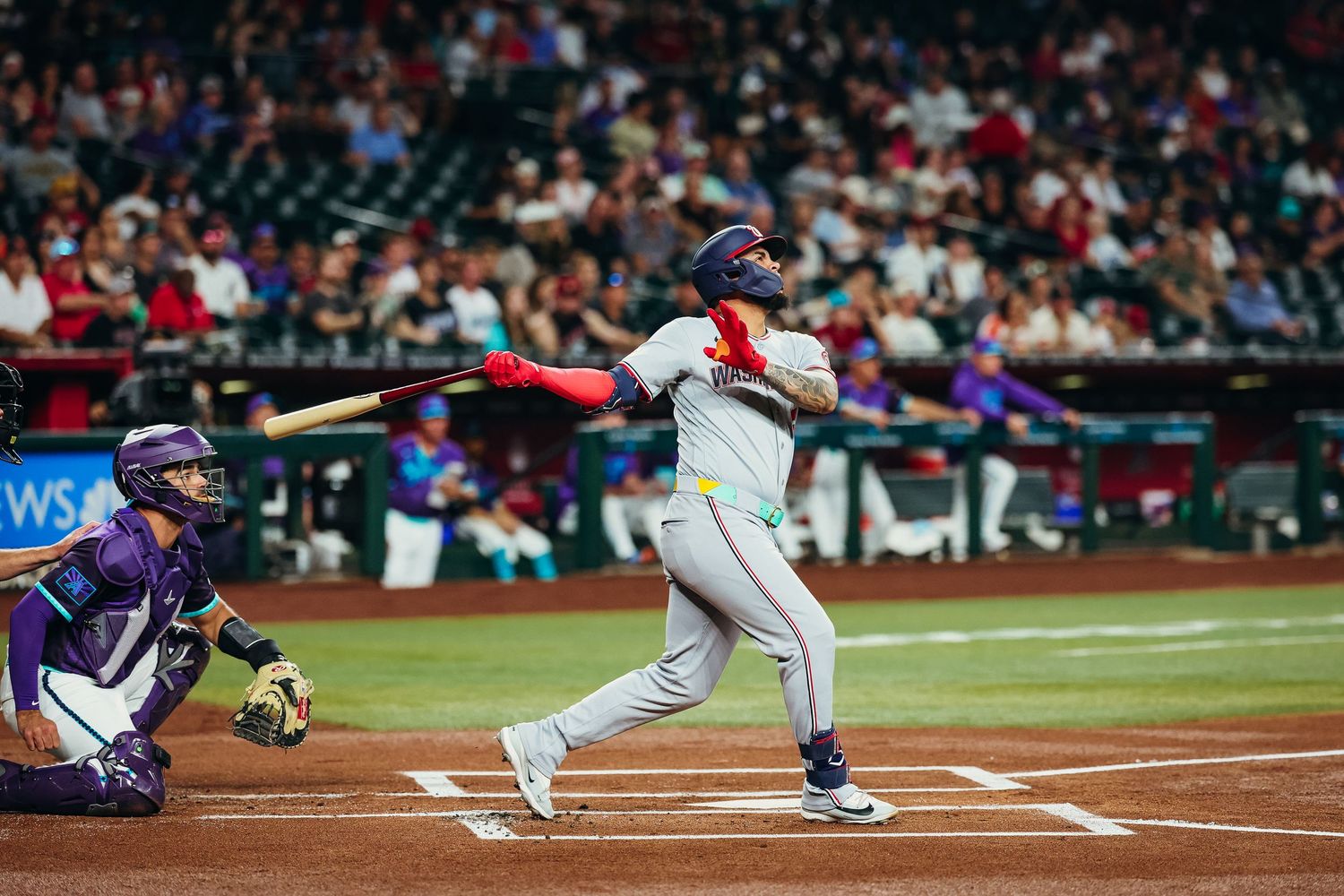 Washington Nationals batter swings at pitch with catcher crouching behind home plate during game.