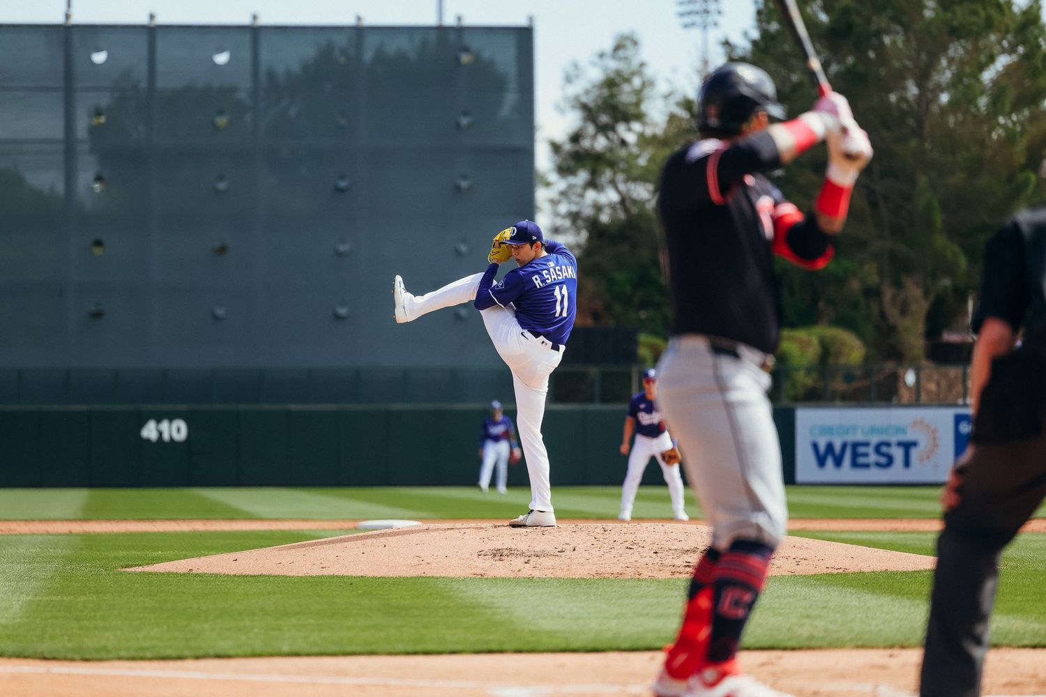 Colorado Rockies pitcher delivering a pitch during a spring training baseball game outdoors.
