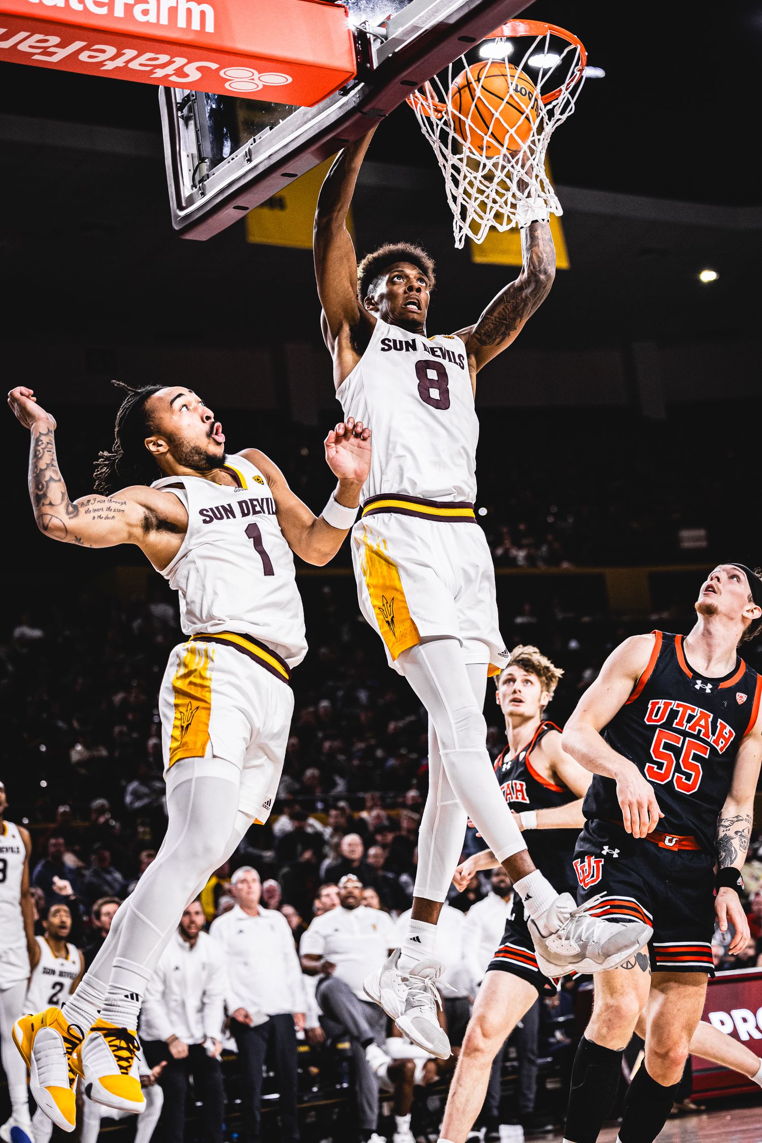 ASU Sun Devils player #8 throws down a powerful dunk while teammate Collins #1 watches against Utah #55.