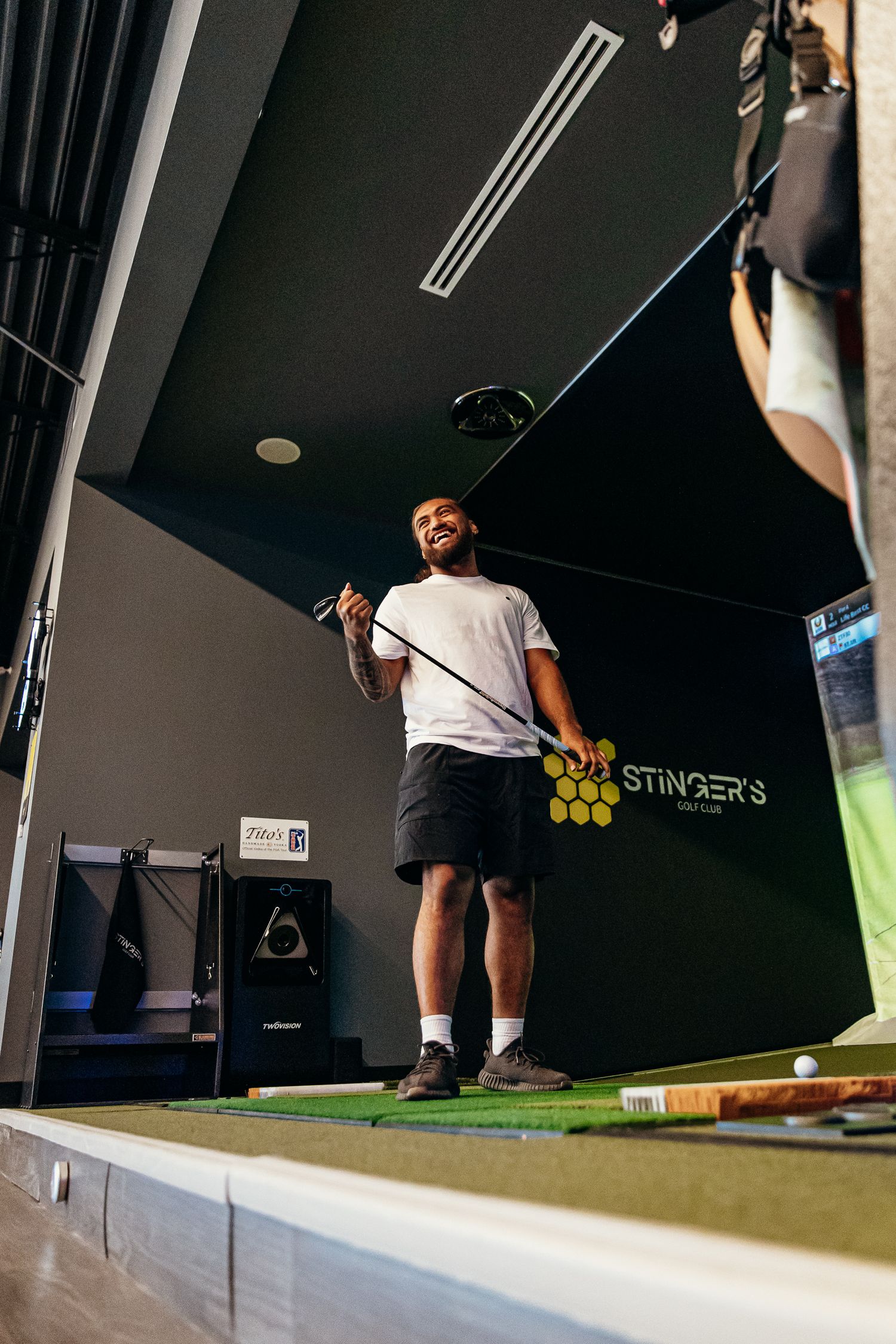 Man smiling while holding a golf club at Stinger's Golf simulator indoor facility.
