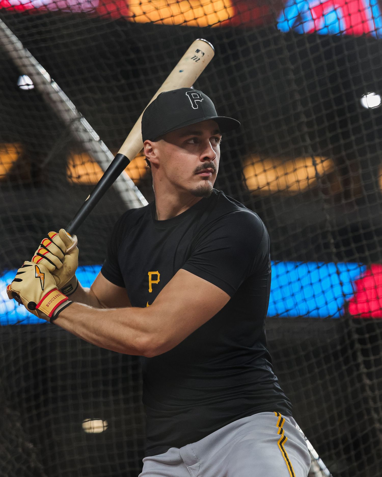Pittsburgh Pirates player takes a batting practice swing in the cage wearing black team gear.