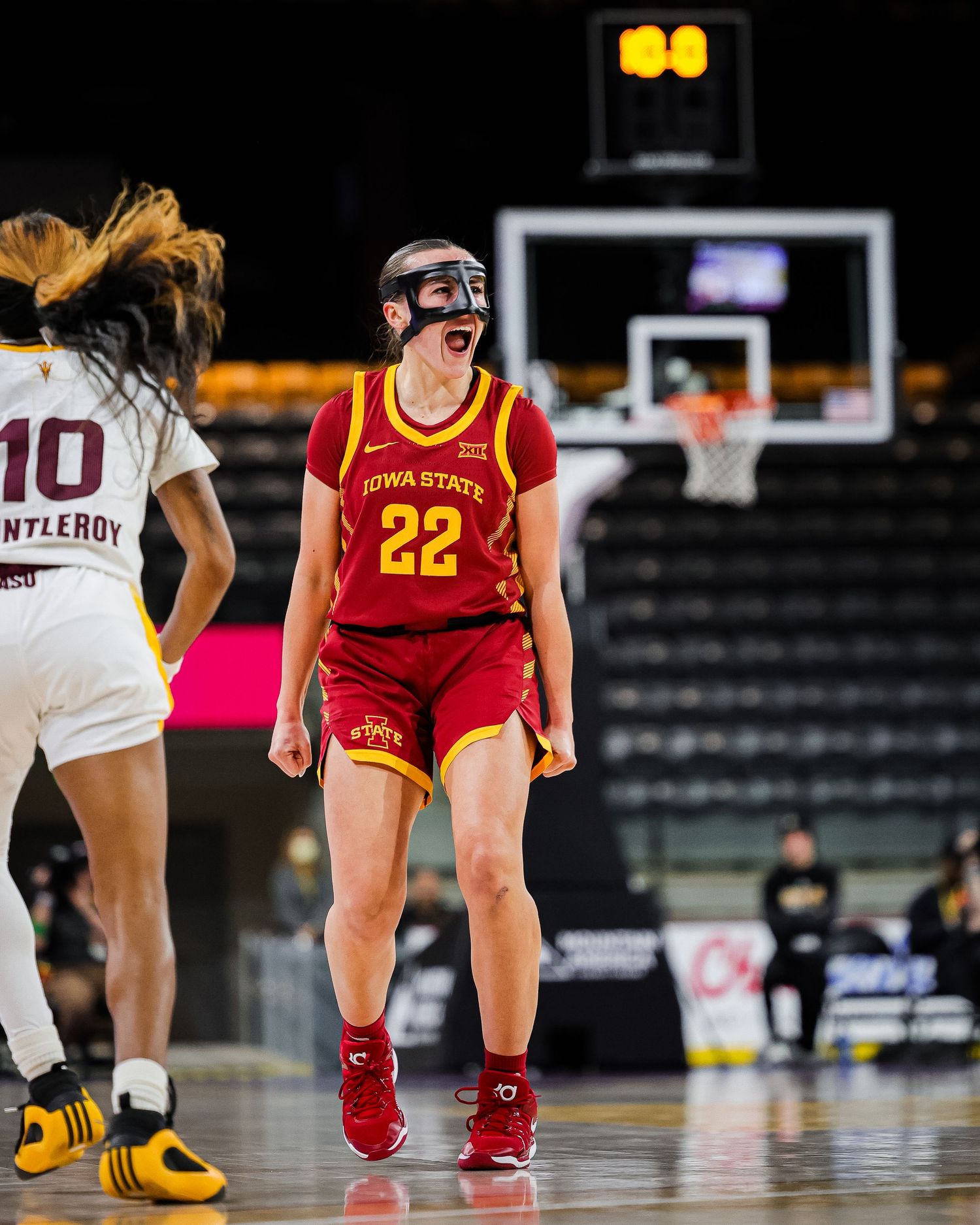 Iowa State Cyclones player #22 celebrates during a womens college basketball game wearing a protective face mask.