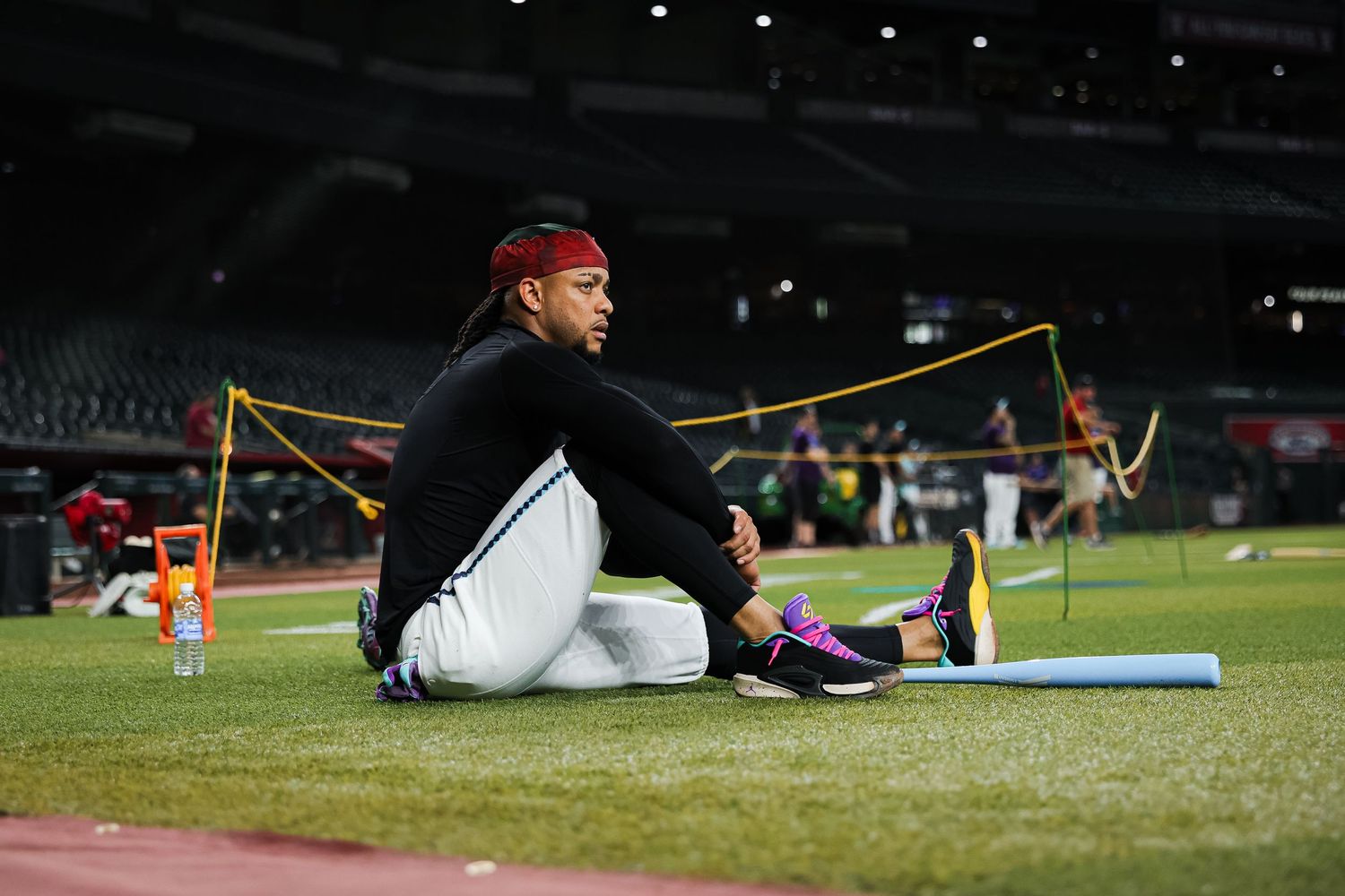 Baseball player stretching on outfield grass during pregame warmups at MLB stadium.