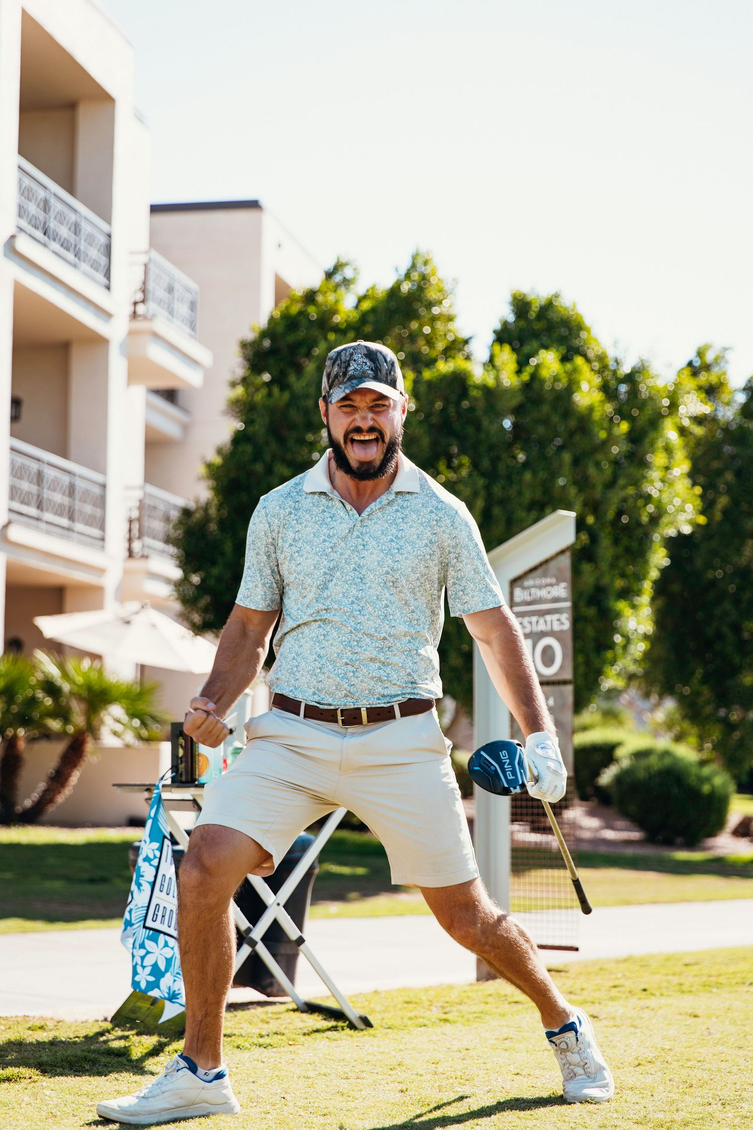 Excited bearded man celebrating on a golf course holding a club during a charity golf event.