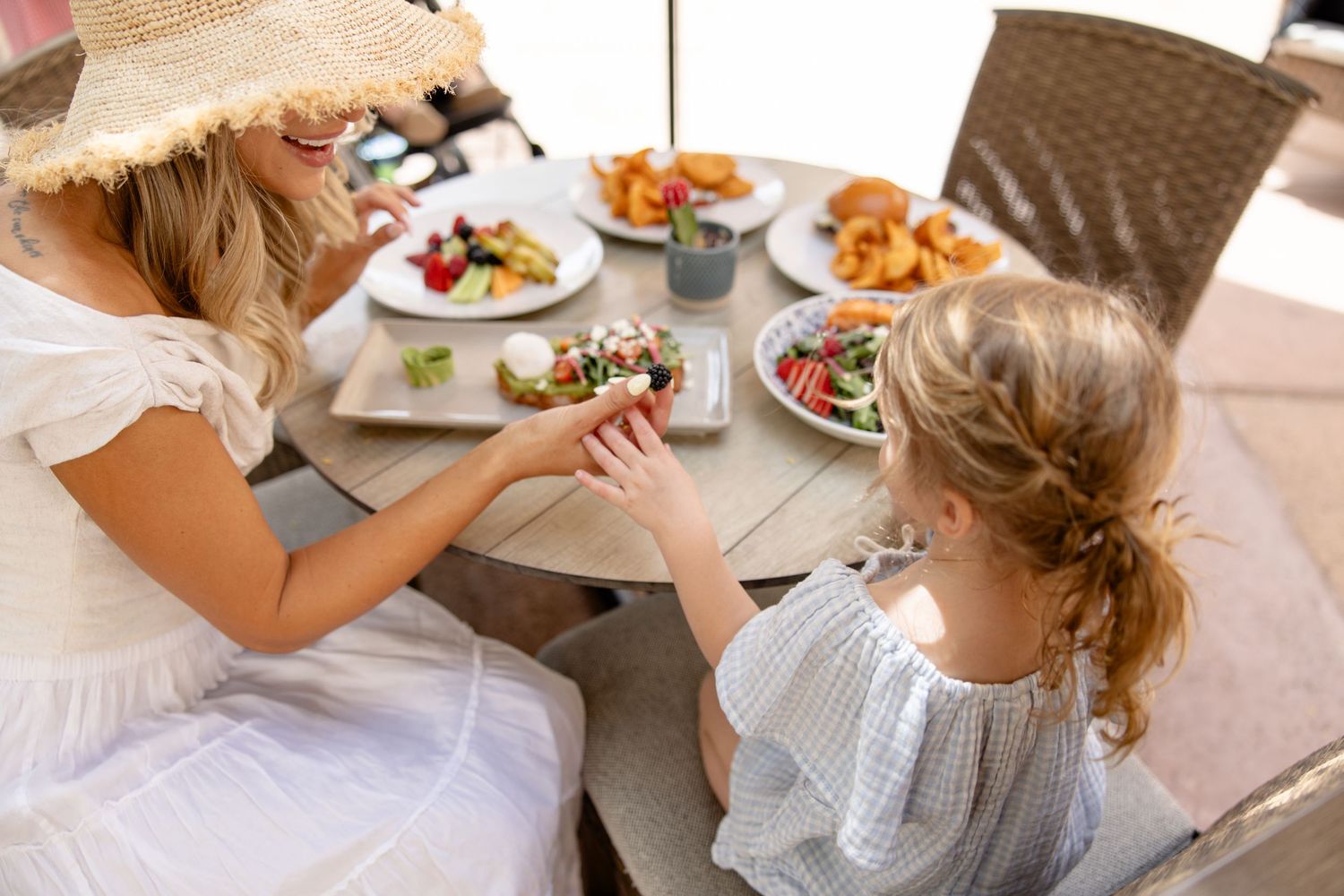 Mother and daughter enjoying a meal together at an outdoor restaurant patio.