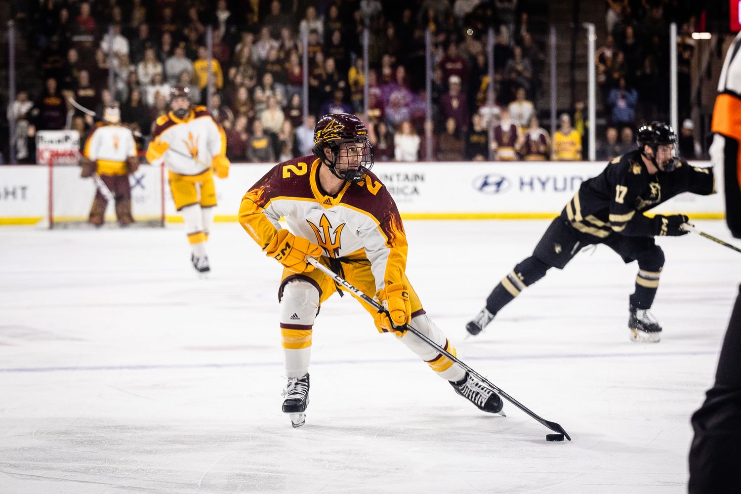 Arizona State Sun Devils hockey player #2 controls the puck during a college ice hockey game.