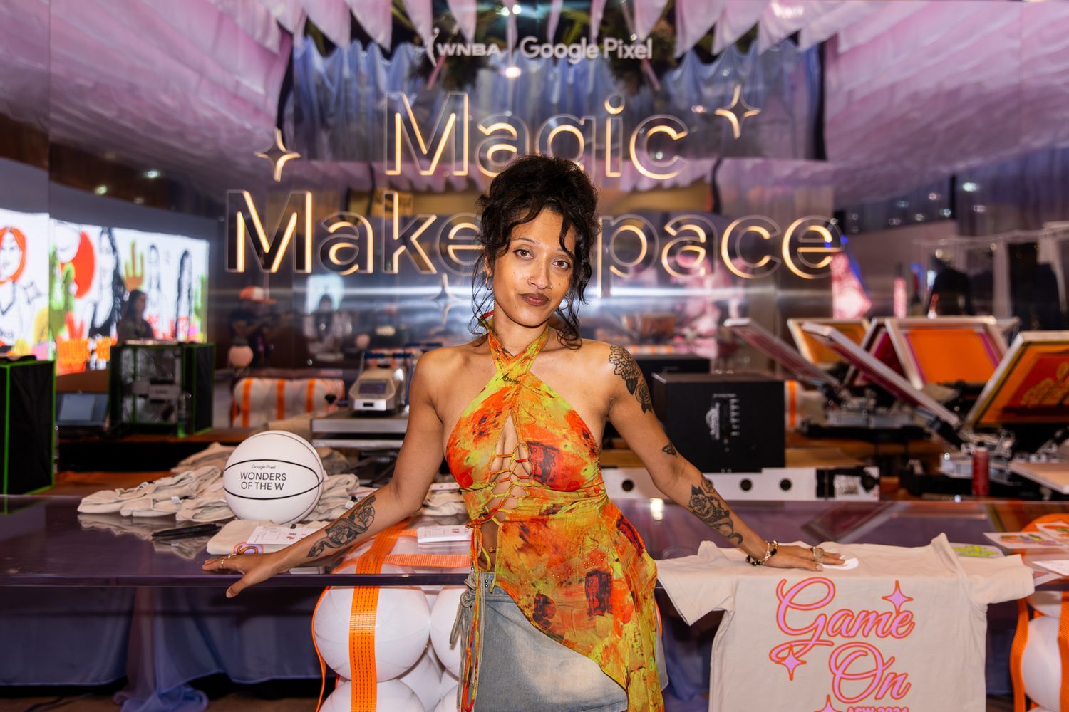 Woman in floral dress posing at Magic Makespace activation booth sponsored by Google Pixel at indoor event.