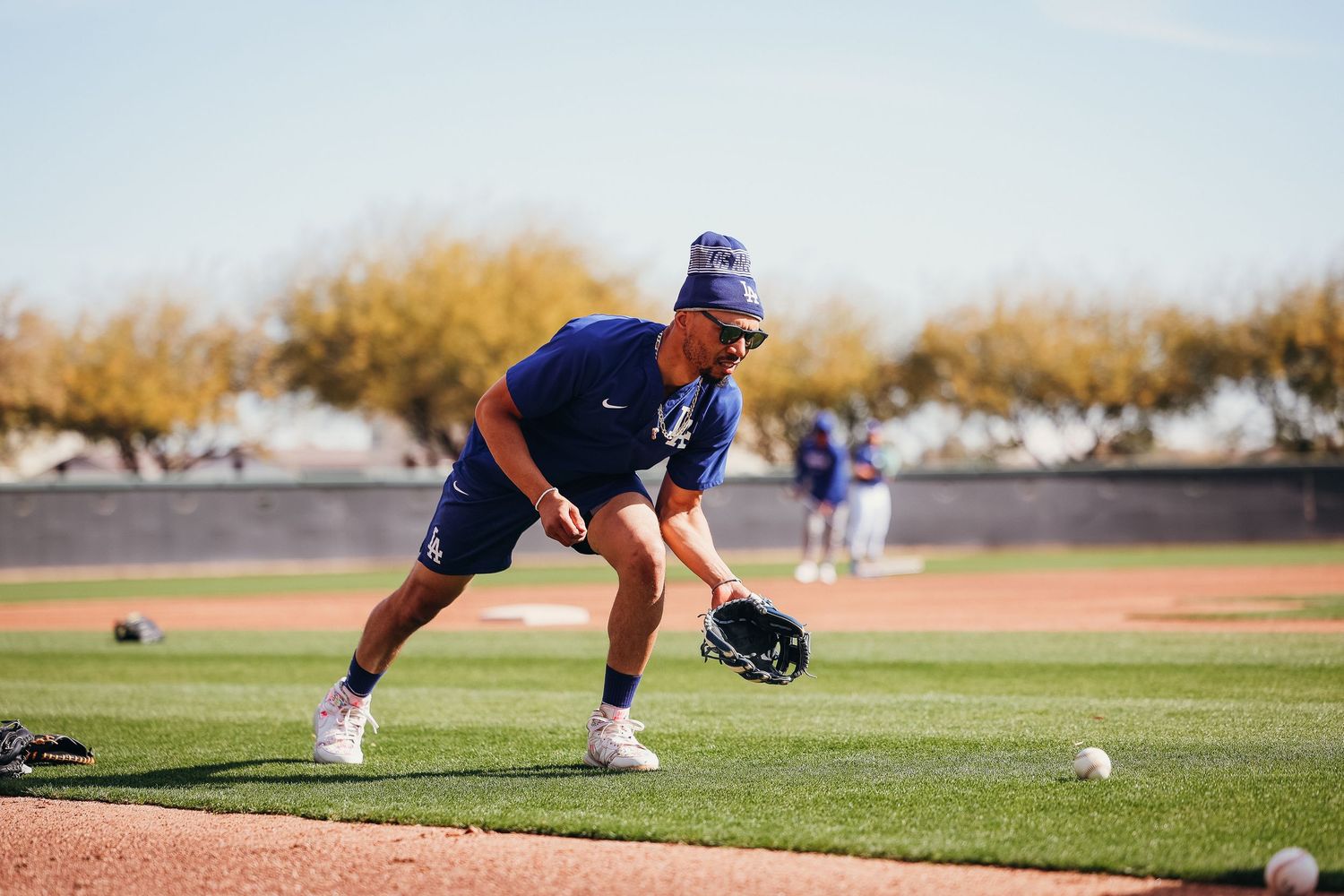 Baseball player fielding ground balls during spring training practice on sunny Arizona field.