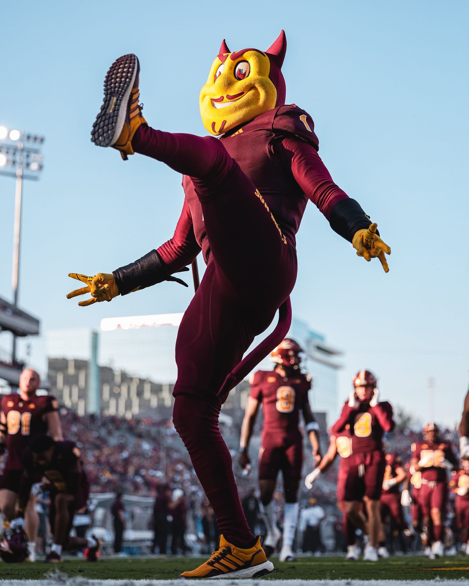 Arizona State Sun Devil mascot Sparky celebrates energetically on football field.