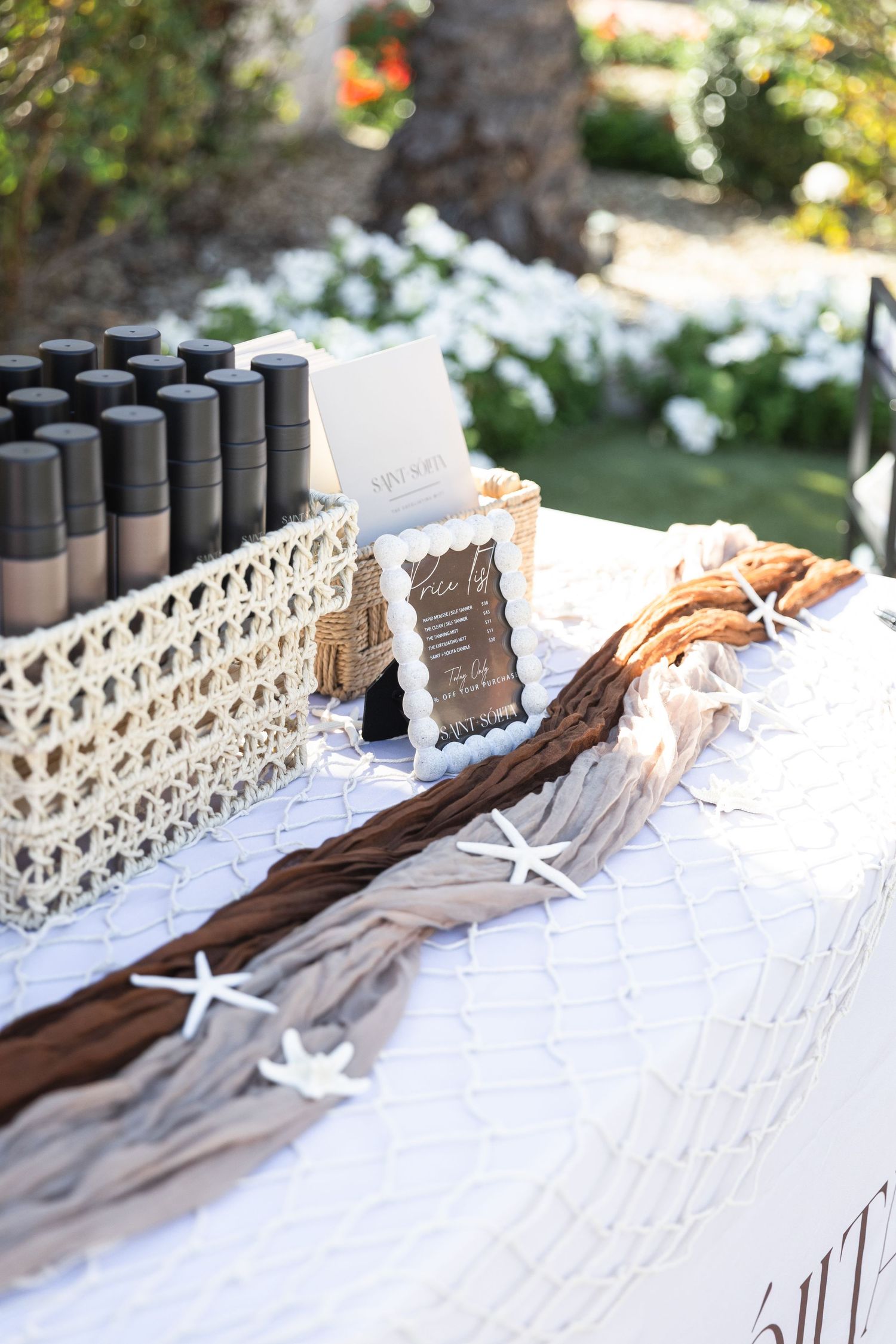 Outdoor beauty product display table with foundation bottles and starfish decorations.