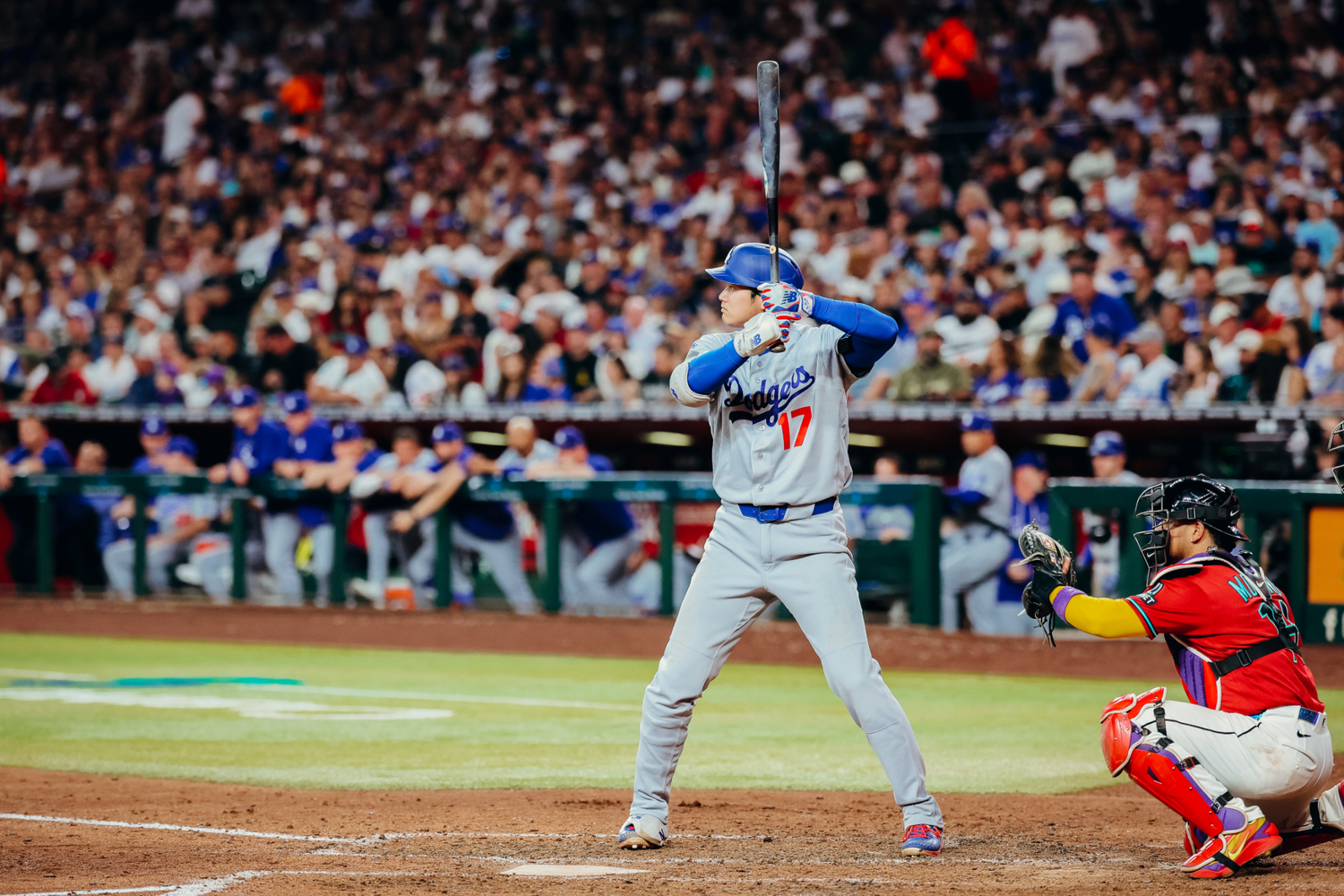Dodgers batter stands ready at home plate during a night MLB game, with catcher and crowd in background.