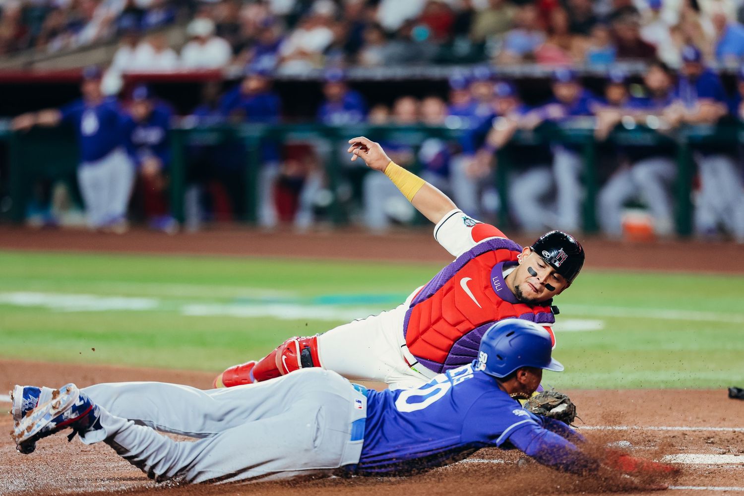 Dodgers baserunner slides into home plate as catcher attempts tag during MLB game.