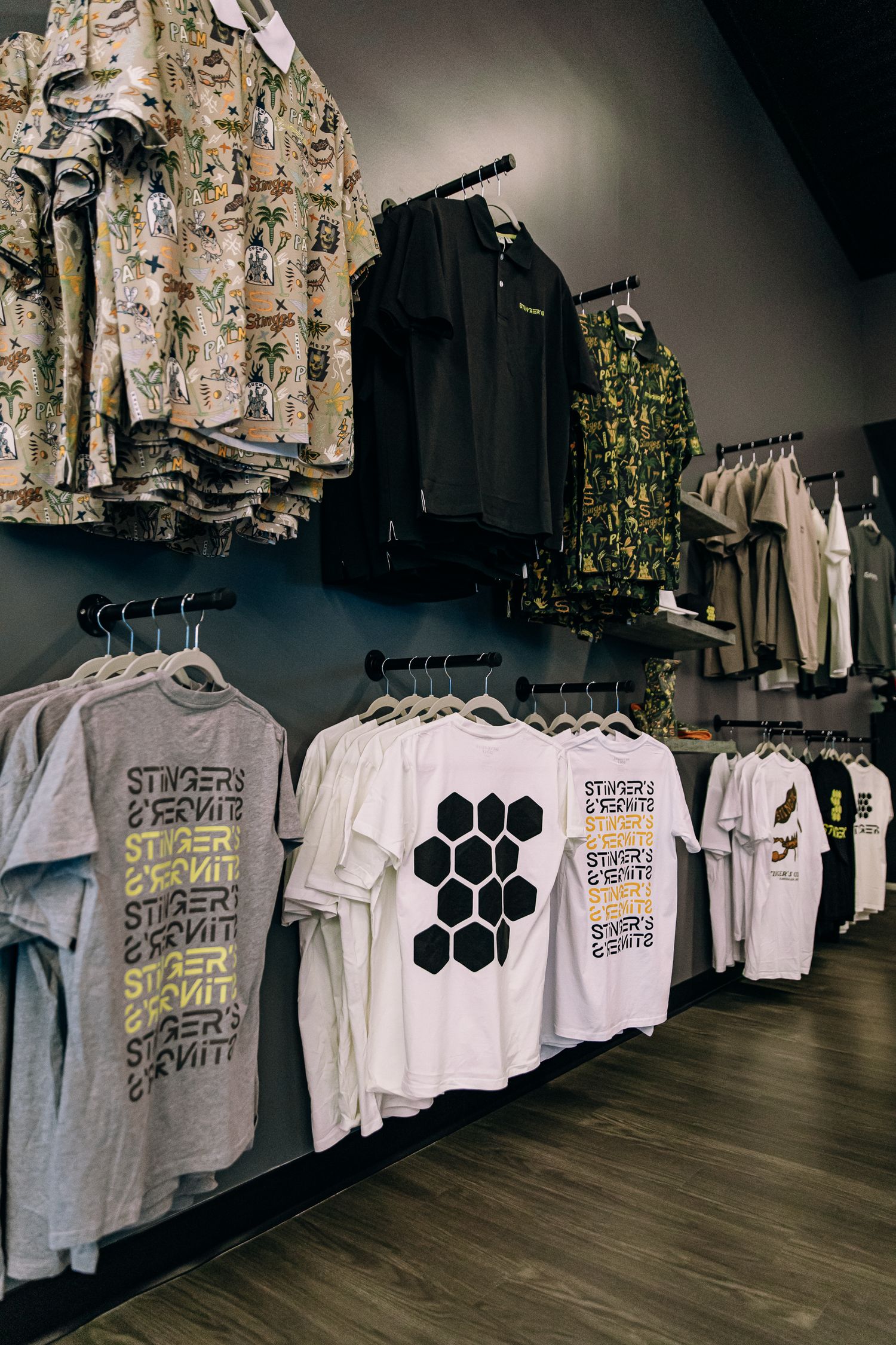 Retail clothing store displaying branded Stingers & Bernite t-shirts on racks with patterned shirts hanging on wall-mounted displays.