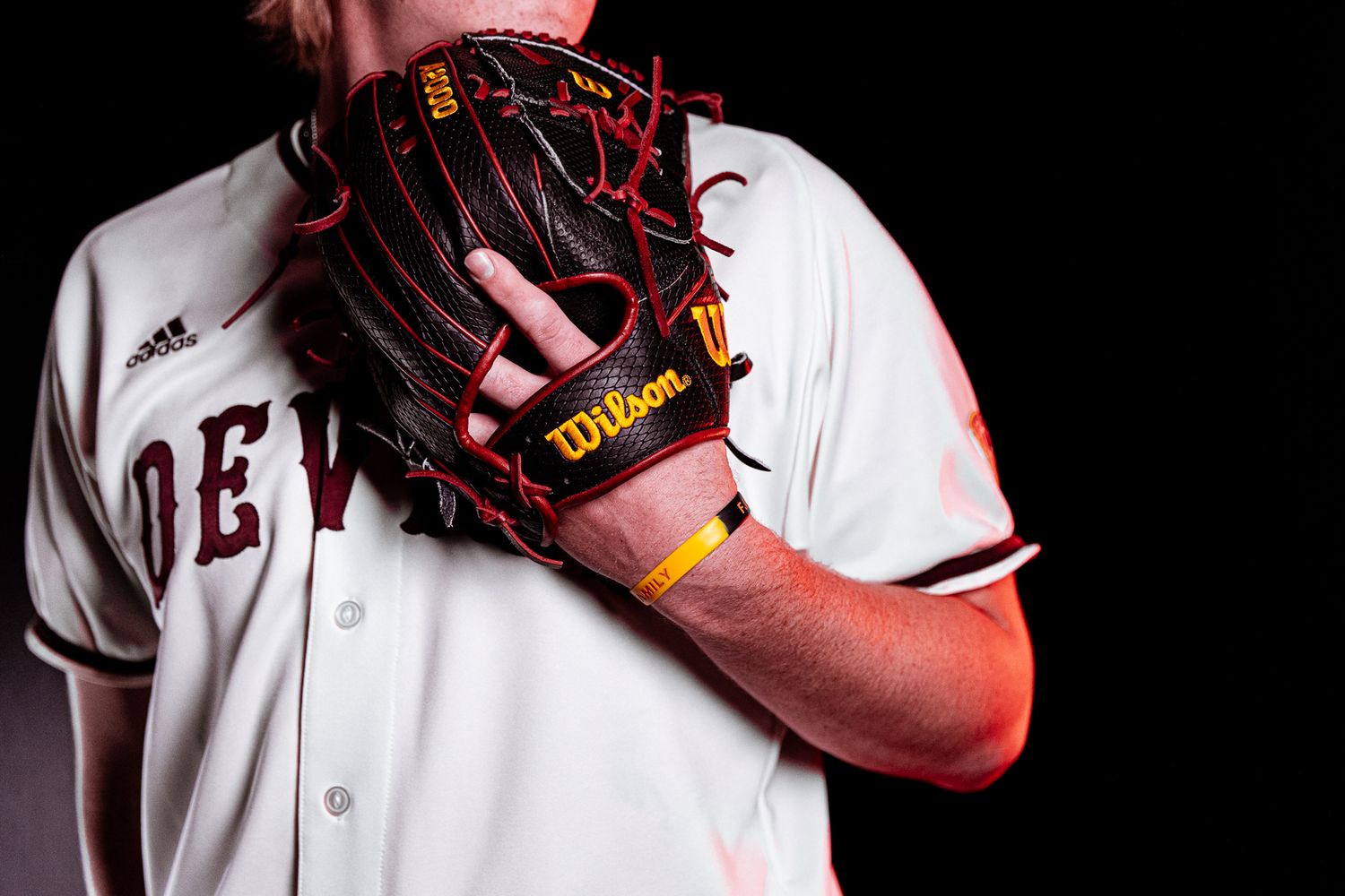 Close-up of Arizona State baseball player holding black and red Wilson glove in Devils uniform.