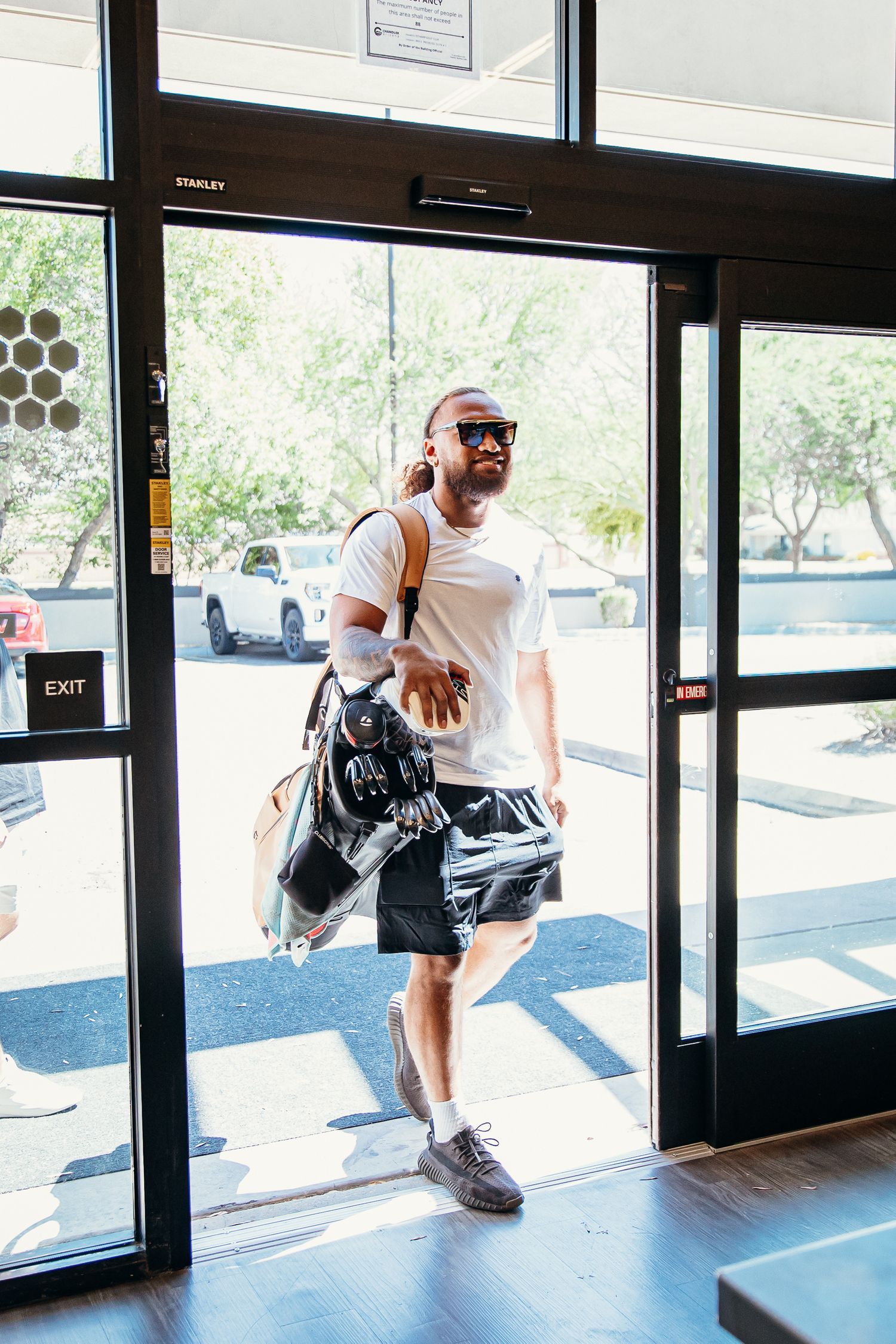 Athletic man carrying golf bags entering Stinger's Golf Club facility.