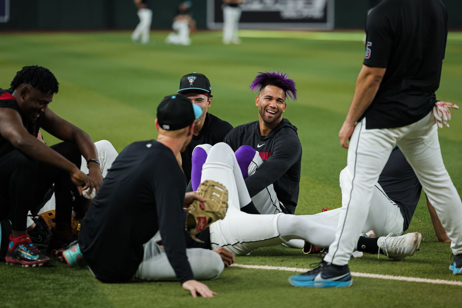 Baseball players relax and laugh together on the field during a pregame warmup session.