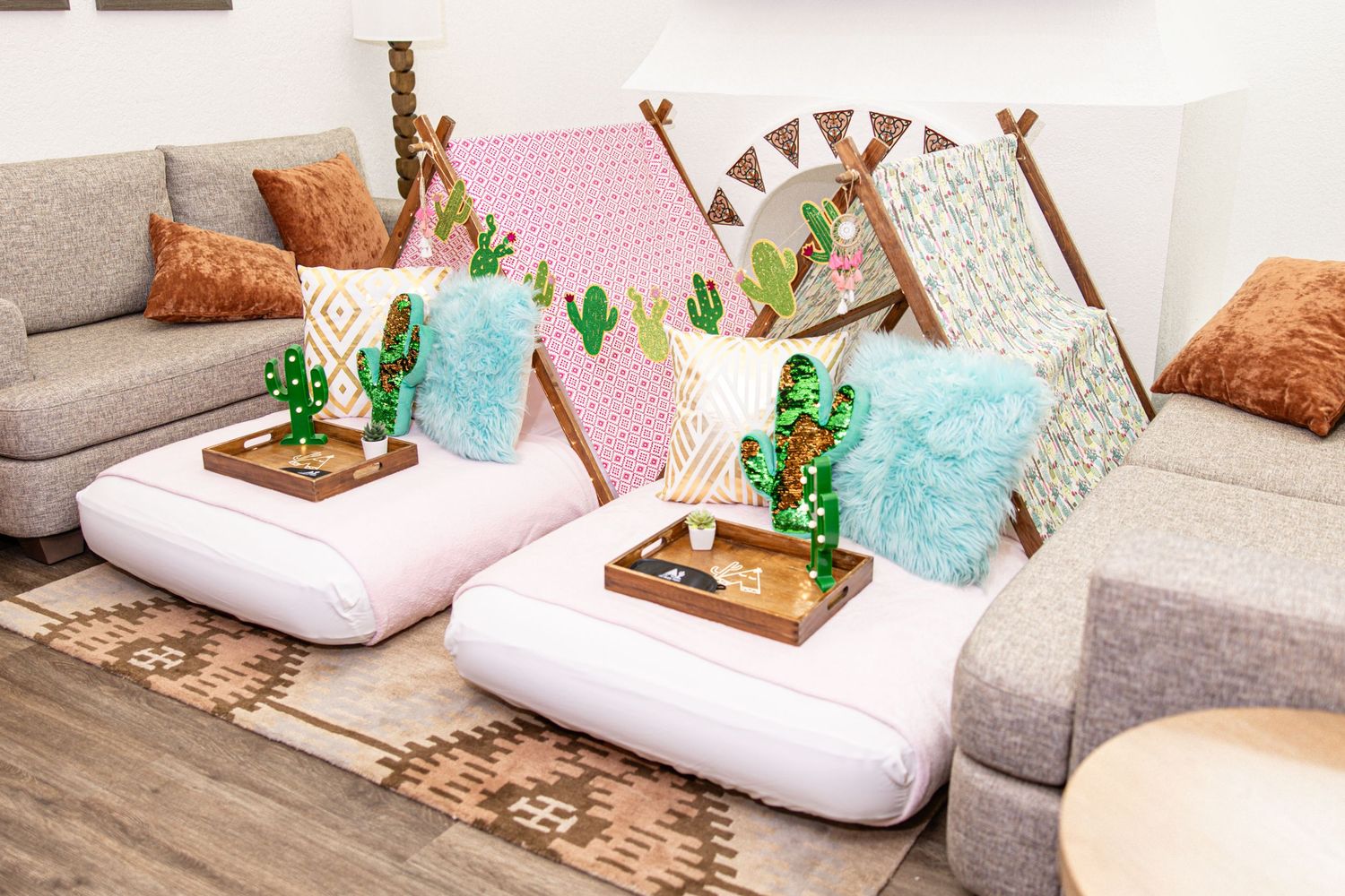 Boho-style kids lounge area with cactus decorations, teepees, fluffy pillows, and patterned rugs.