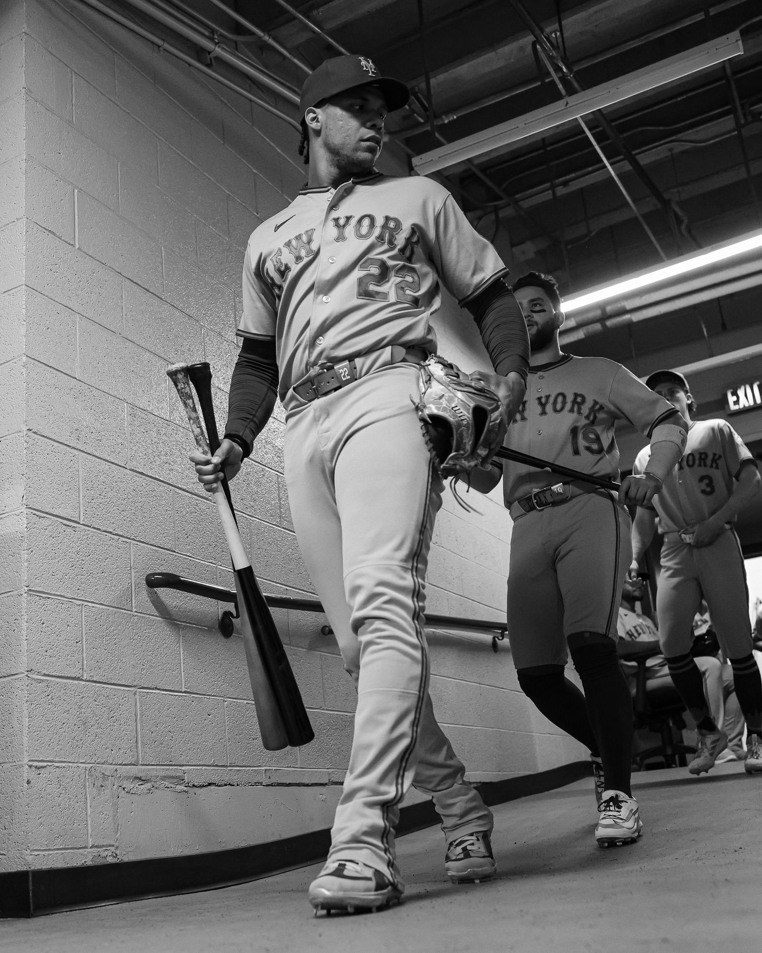 New York Mets player #23 walks through the stadium tunnel holding a baseball bat in black and white.