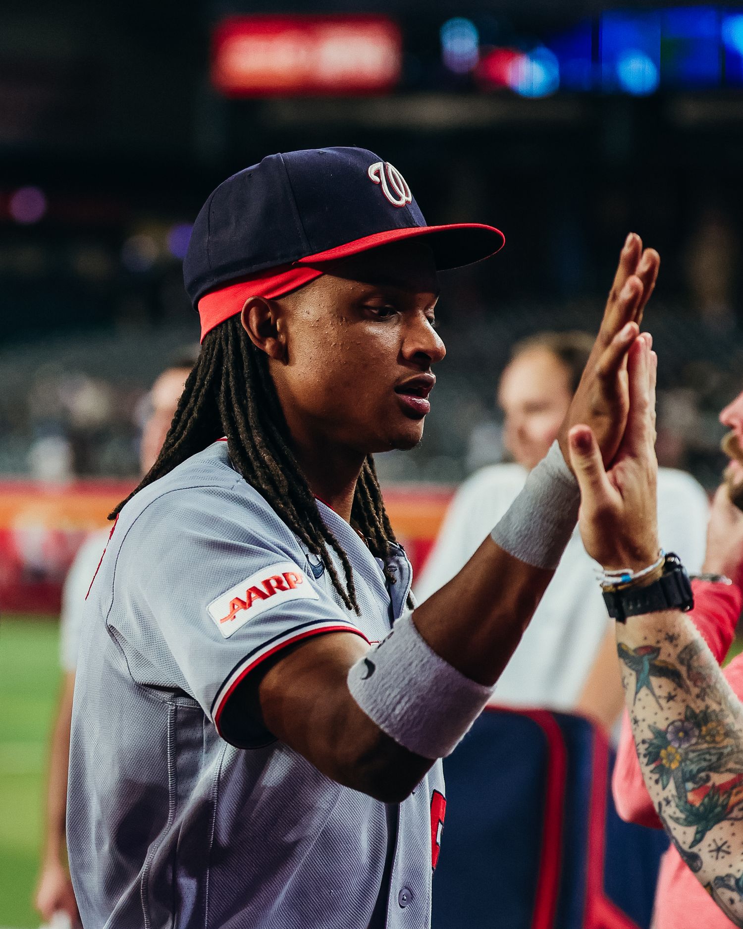 Washington Nationals player with dreadlocks claps hands during post-game celebration on the field.
