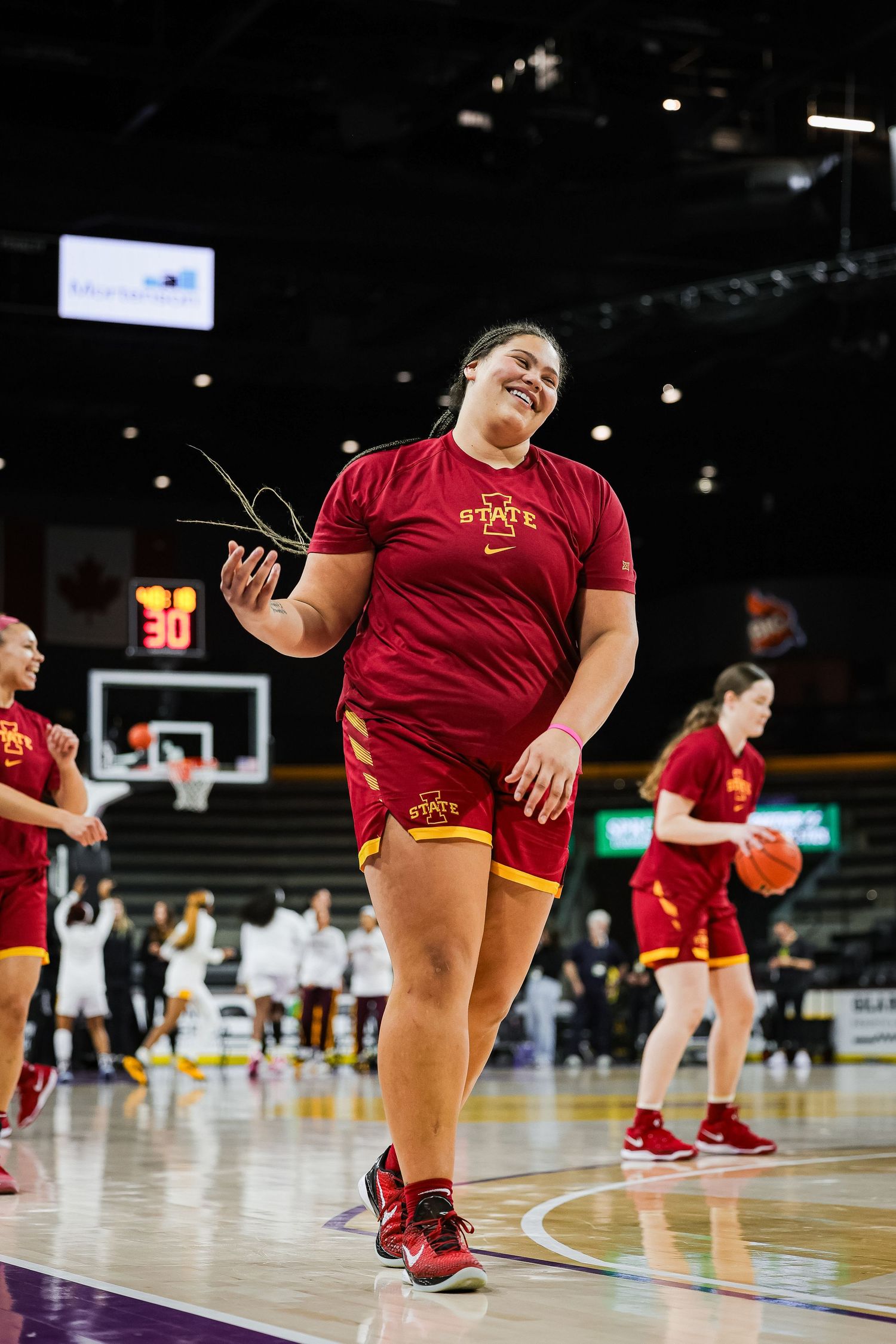 Iowa State Cyclones female athlete smiles while walking on the basketball court during pre-game warmups.