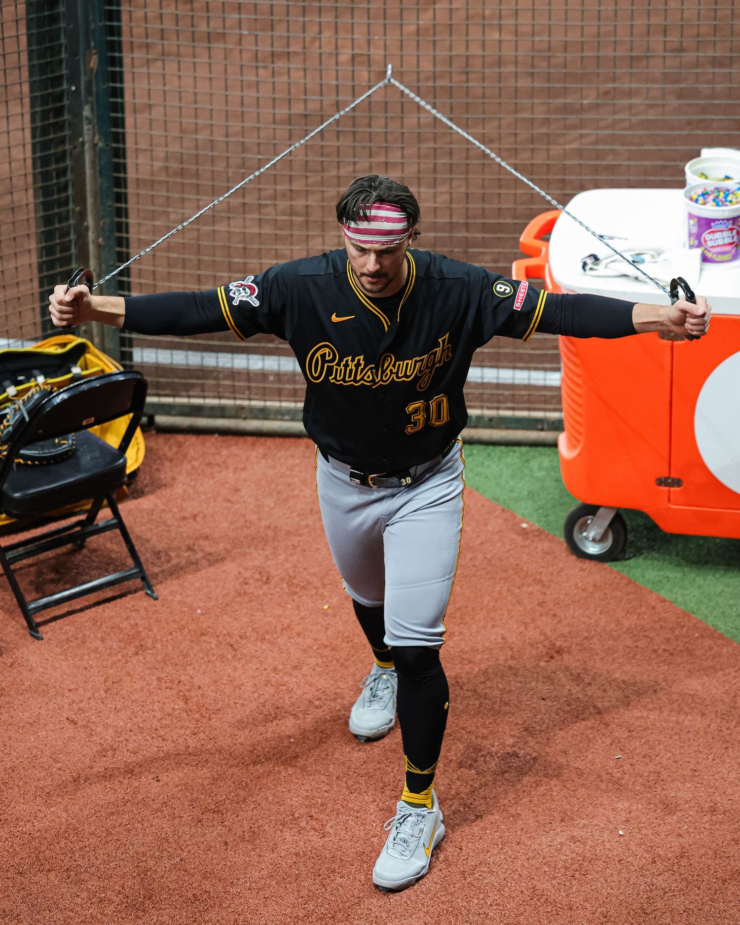 Pittsburgh Pirates #30 stretches with resistance bands in the dugout before a game.