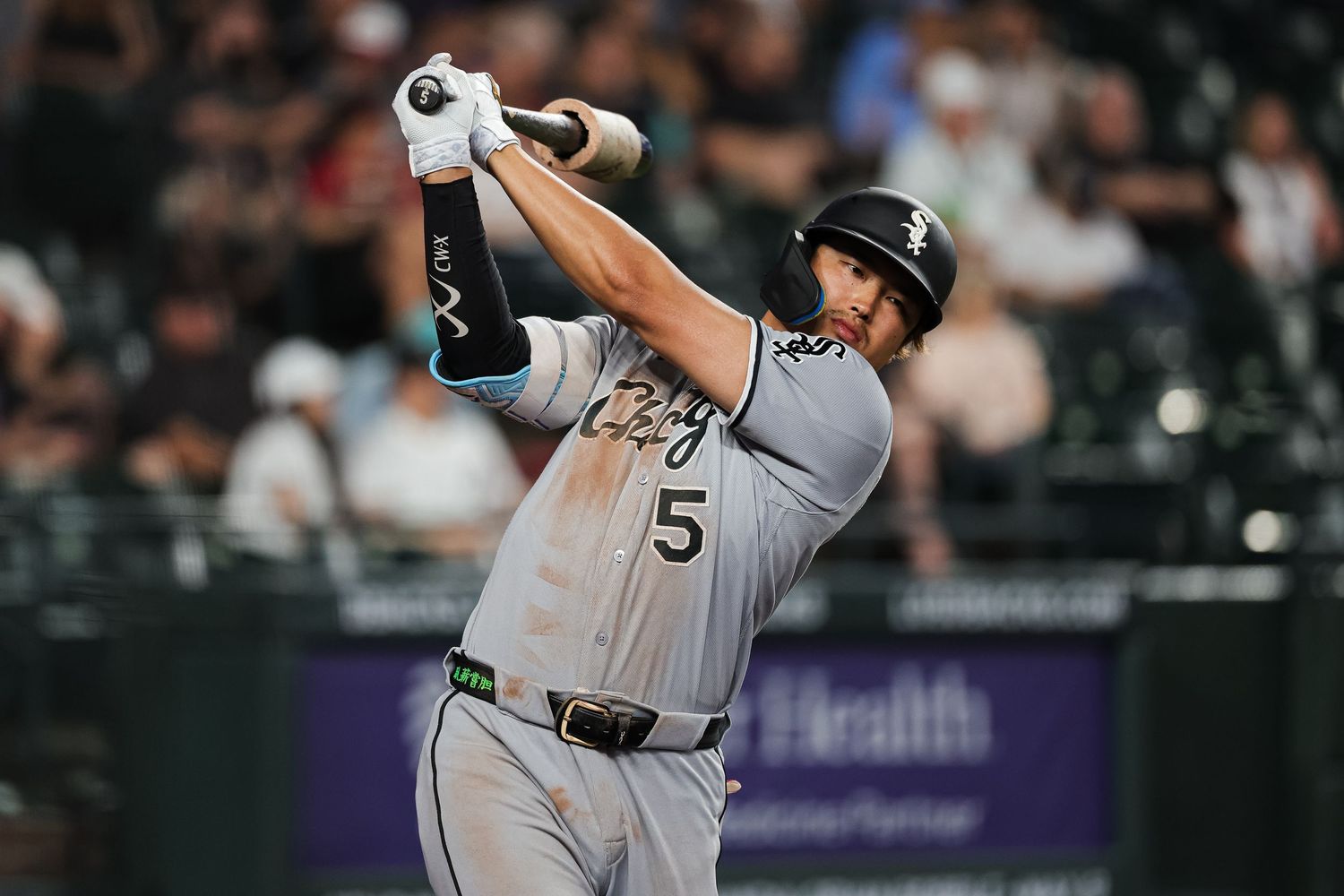 Chicago White Sox batter #5 swings during a night game in gray away uniform.