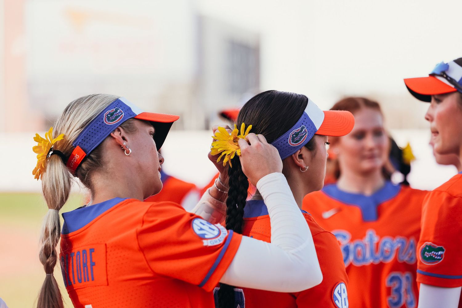 Florida Gators softball players adjust their gear and hair accessories before a game.
