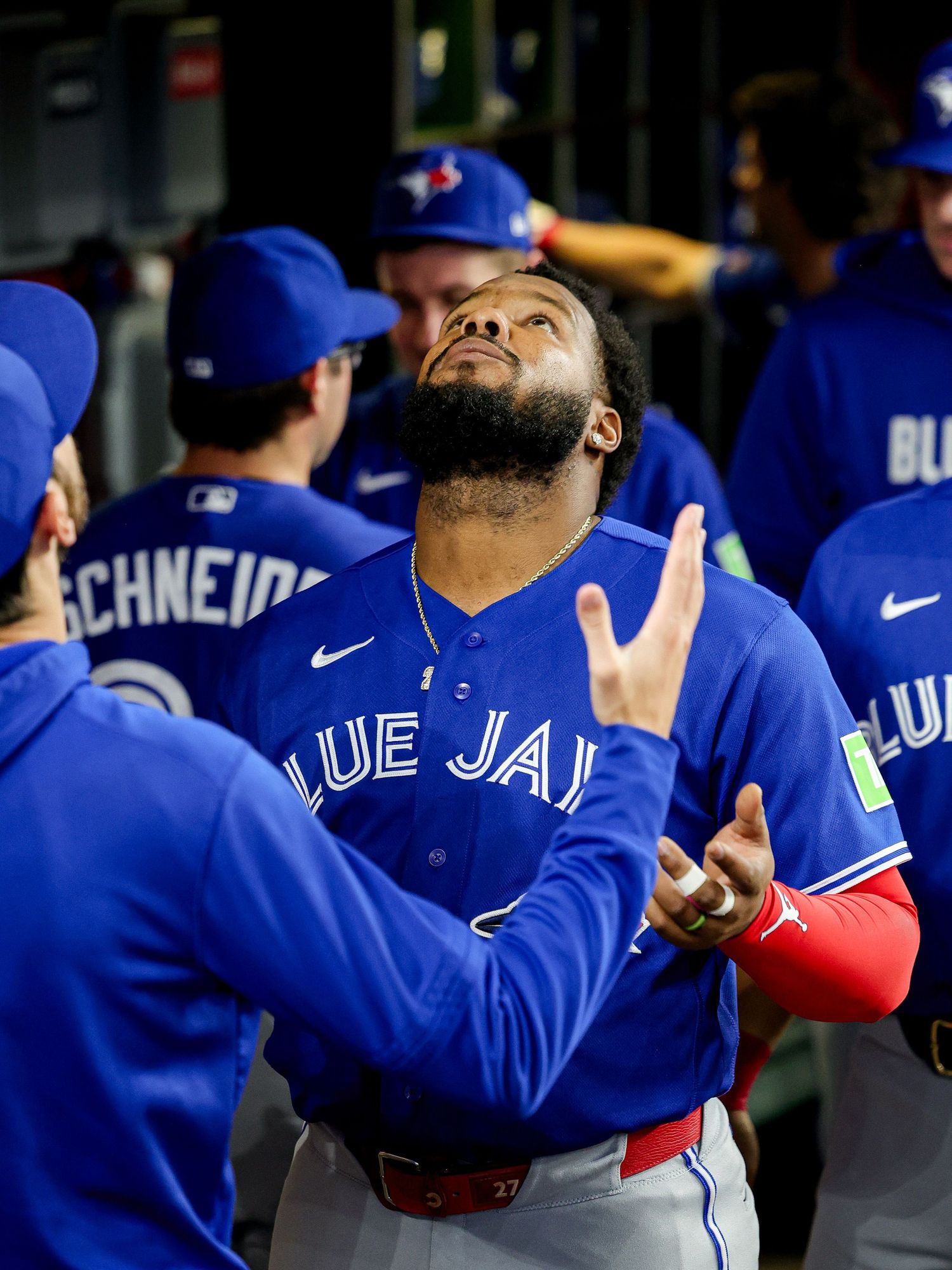 Toronto Blue Jays player looks skyward and gestures in the dugout during a game.