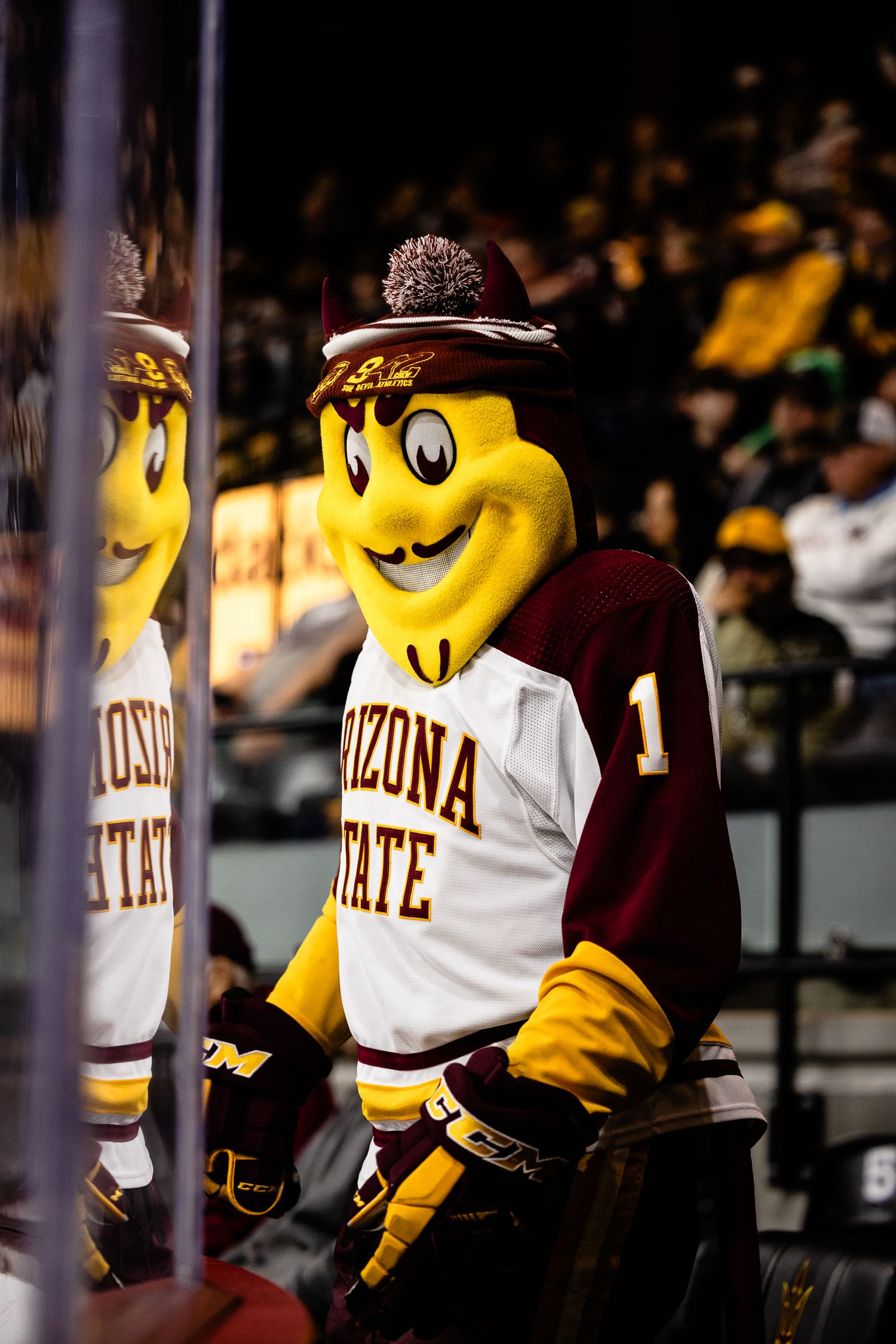 Arizona State Sun Devils mascot Sparky poses in a hockey jersey at a college hockey game.