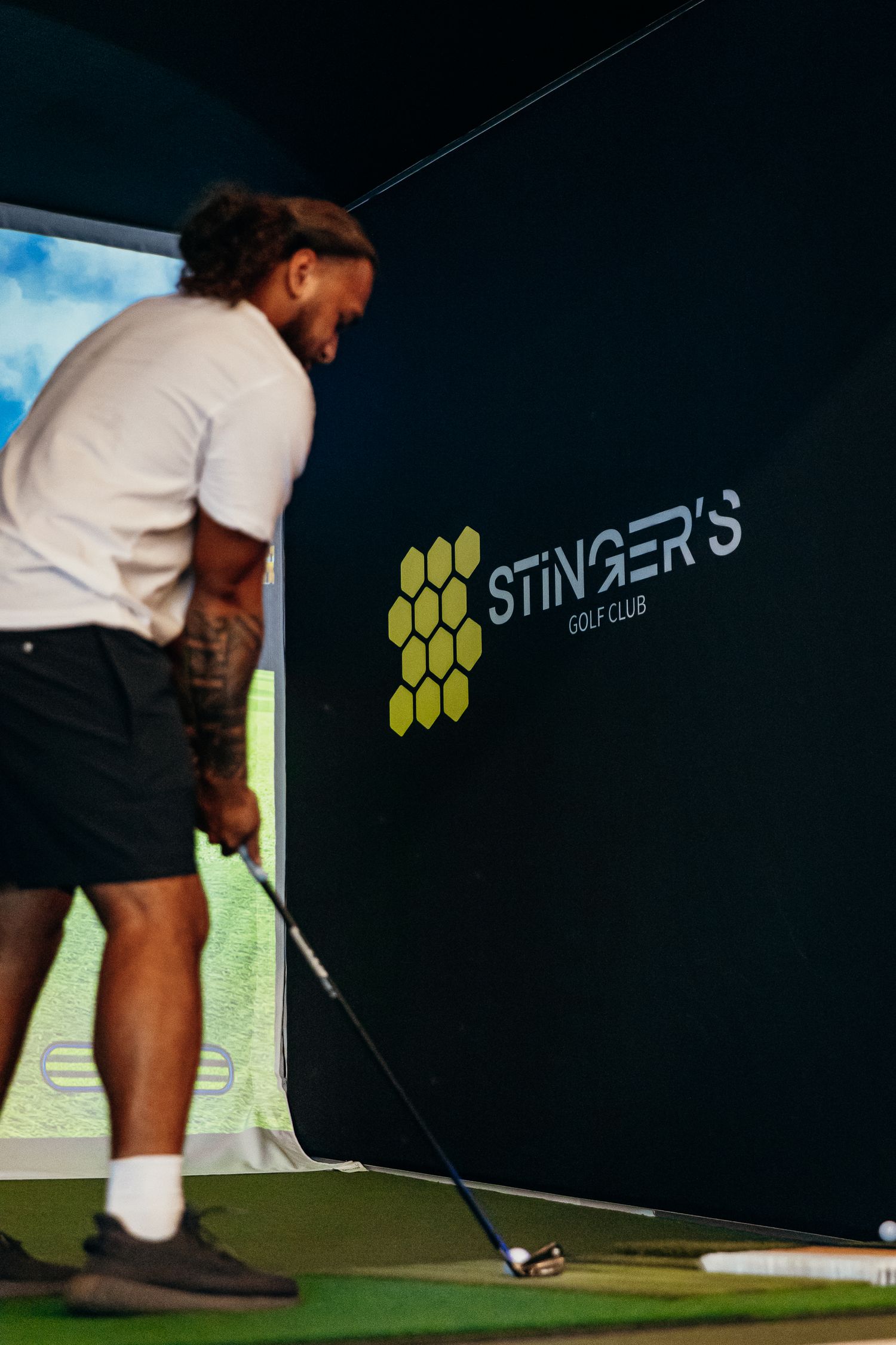 Man practicing golf swing at Stinger's Golf Club indoor simulator bay.
