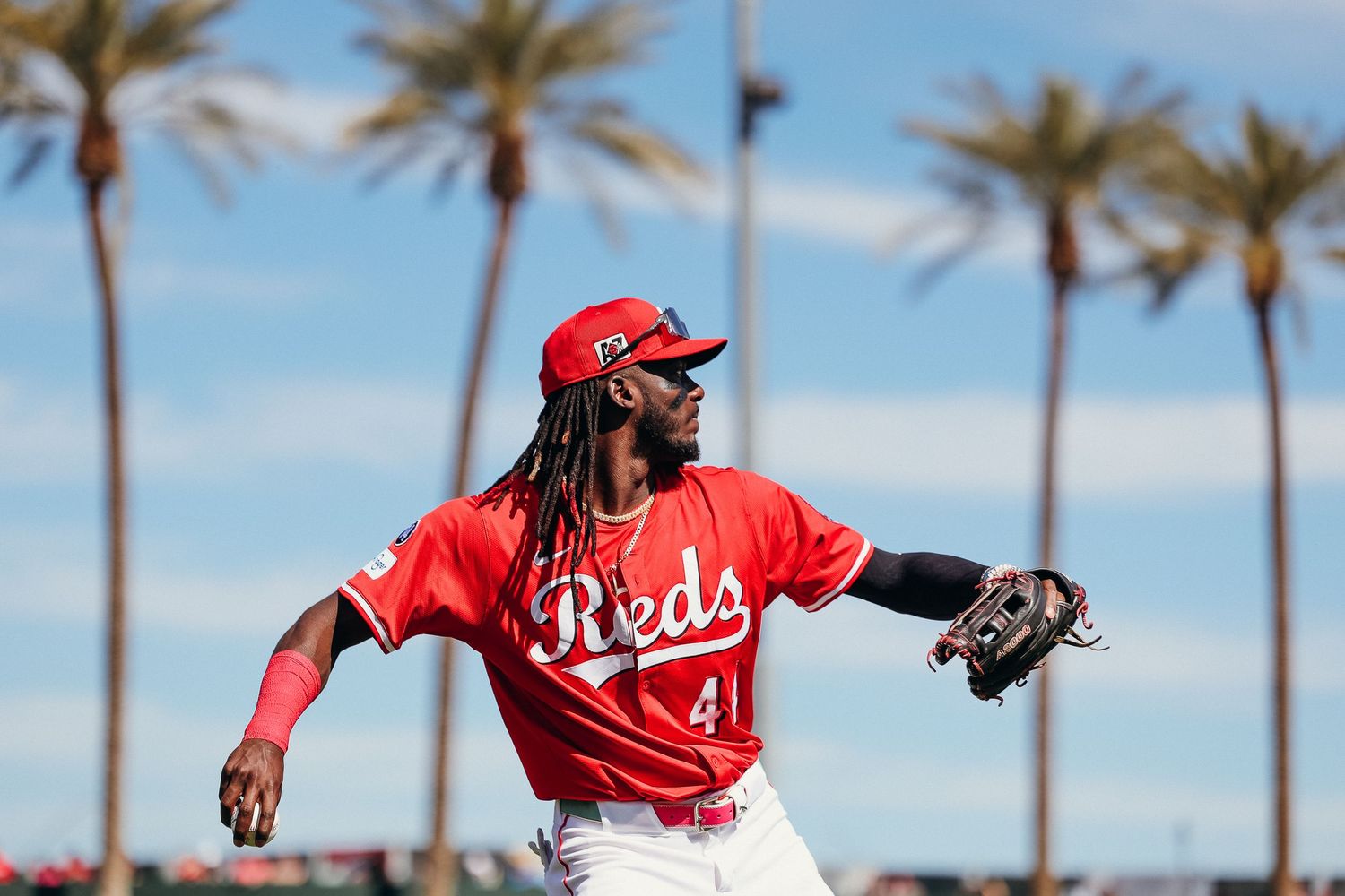 Cincinnati Reds player number 41 fielding in red uniform with palm trees in the background.